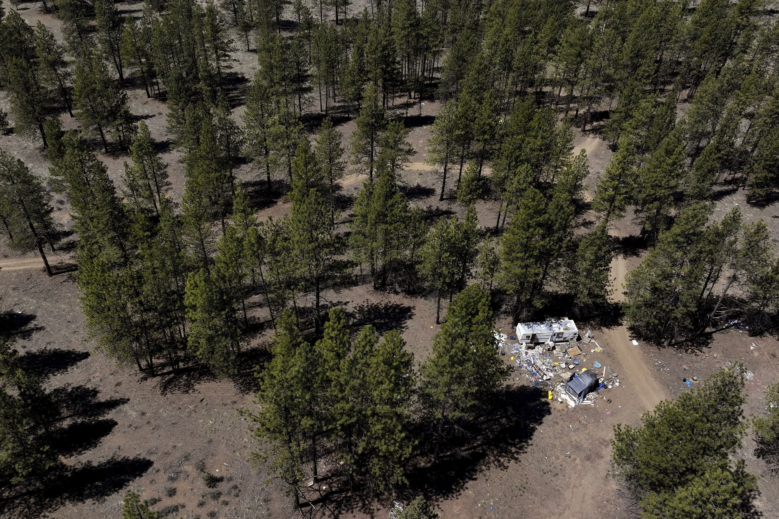Debris lies scattered around a trailer at a homeless encampment in Deschutes National Forest, Thursday, May 1, 2025, near Bend, Ore.