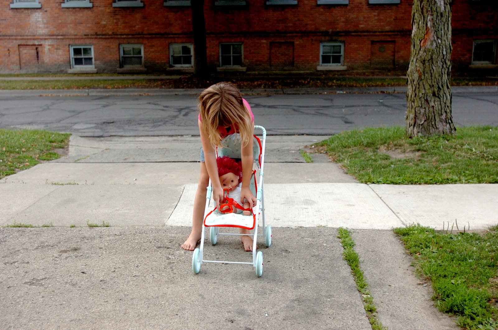Jasmine Stanfill, 4, straps her doll in a stroller in Monroe, Mich. Jasmine and her sister, Shaelyn, took turns walking up and down the sidewalk with their new stroller.