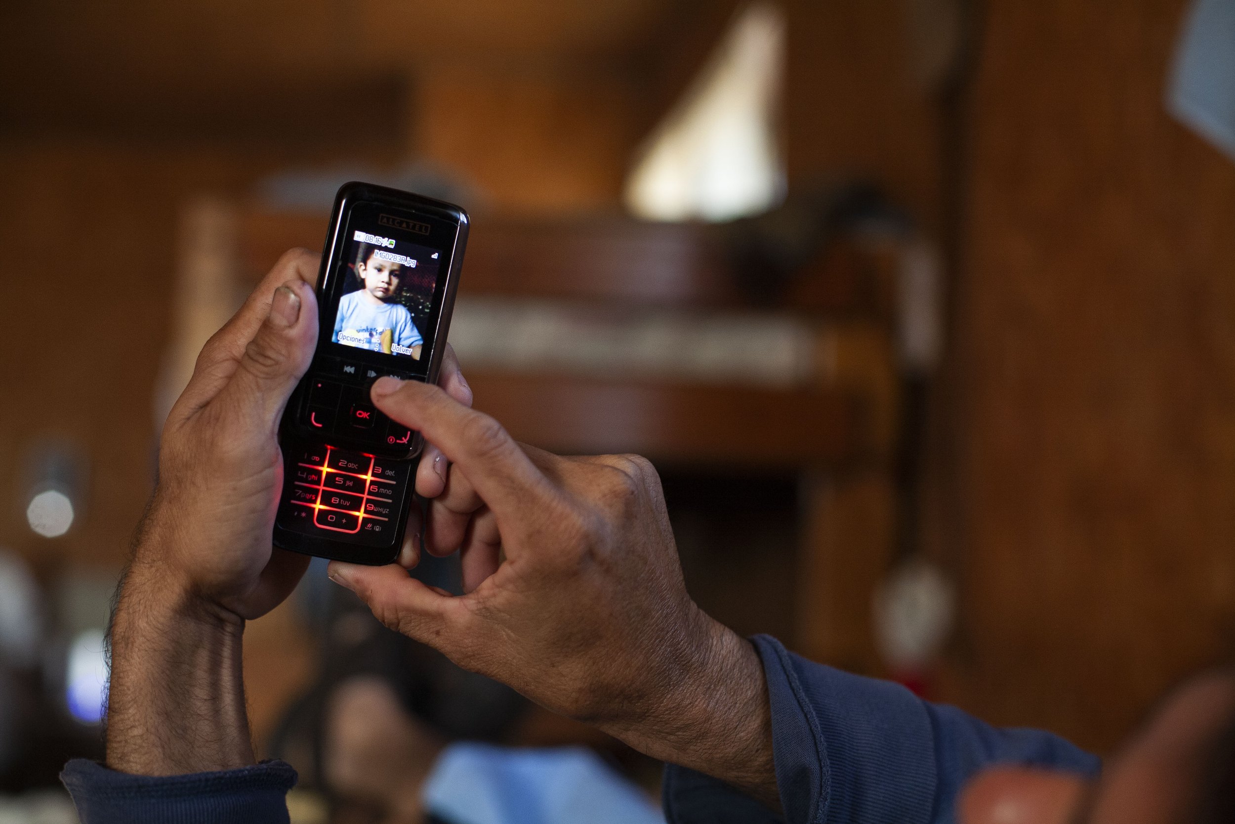 Angel Rodriguez Castillo, looks at a photo of his son Maximo, 1, on his birthday.