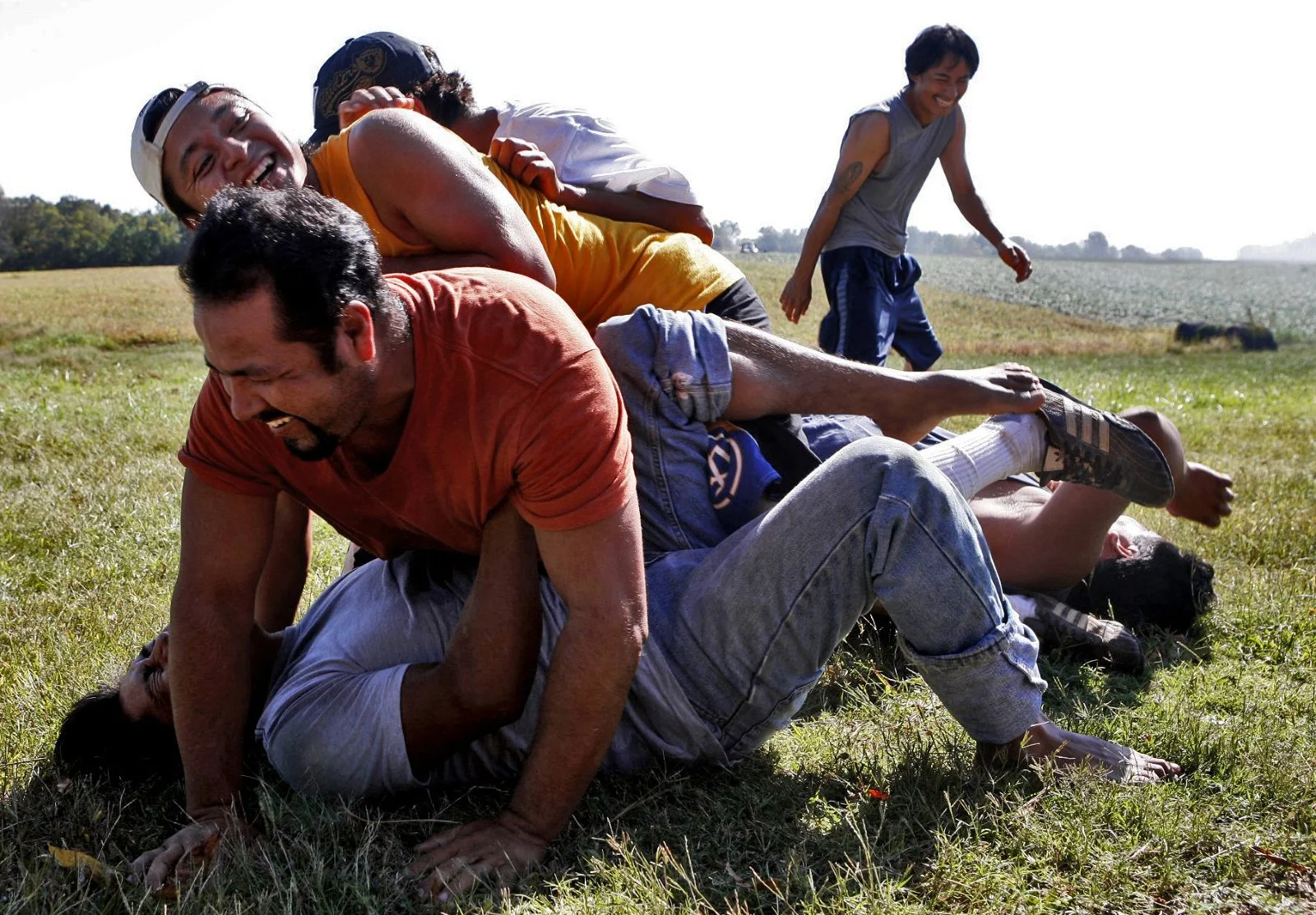 During a slow day several of the men pass the time with the soccer ball. Martinez, curls up on the ground outside of their home after being accidentally kicked in the groin. In an effort to cheer him up Carlos Gomora, jumps on top of him and others f