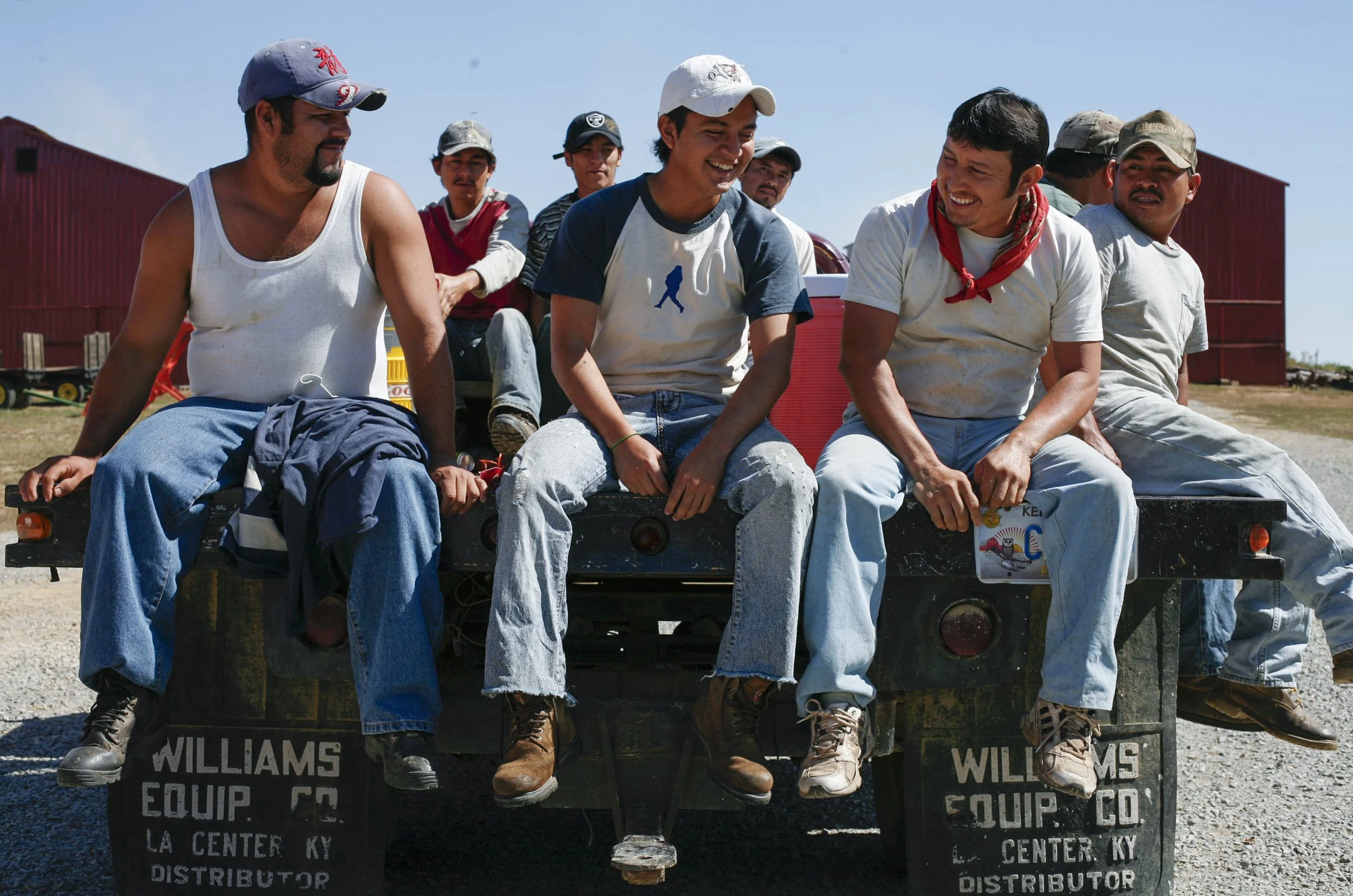 Migrant workers ride on a flatbed trailer to their next job on the farm.