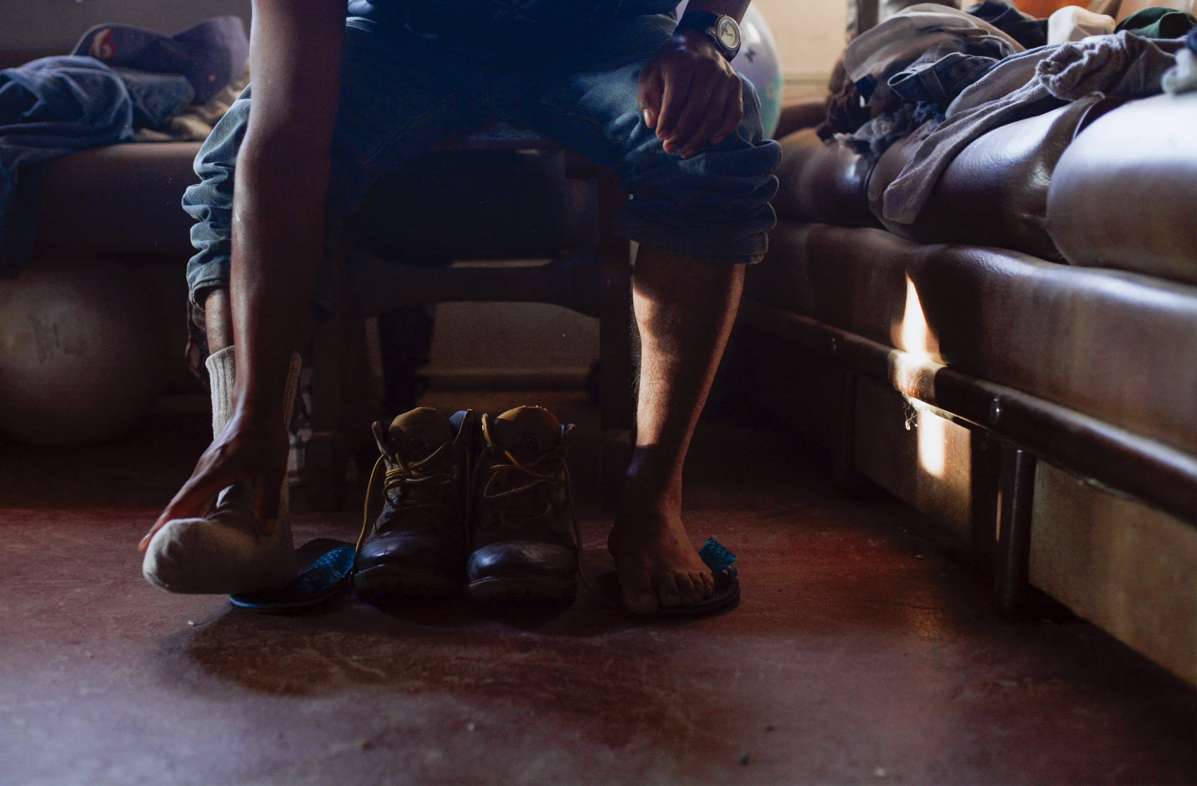 A migrant worker takes off his shoes after working.