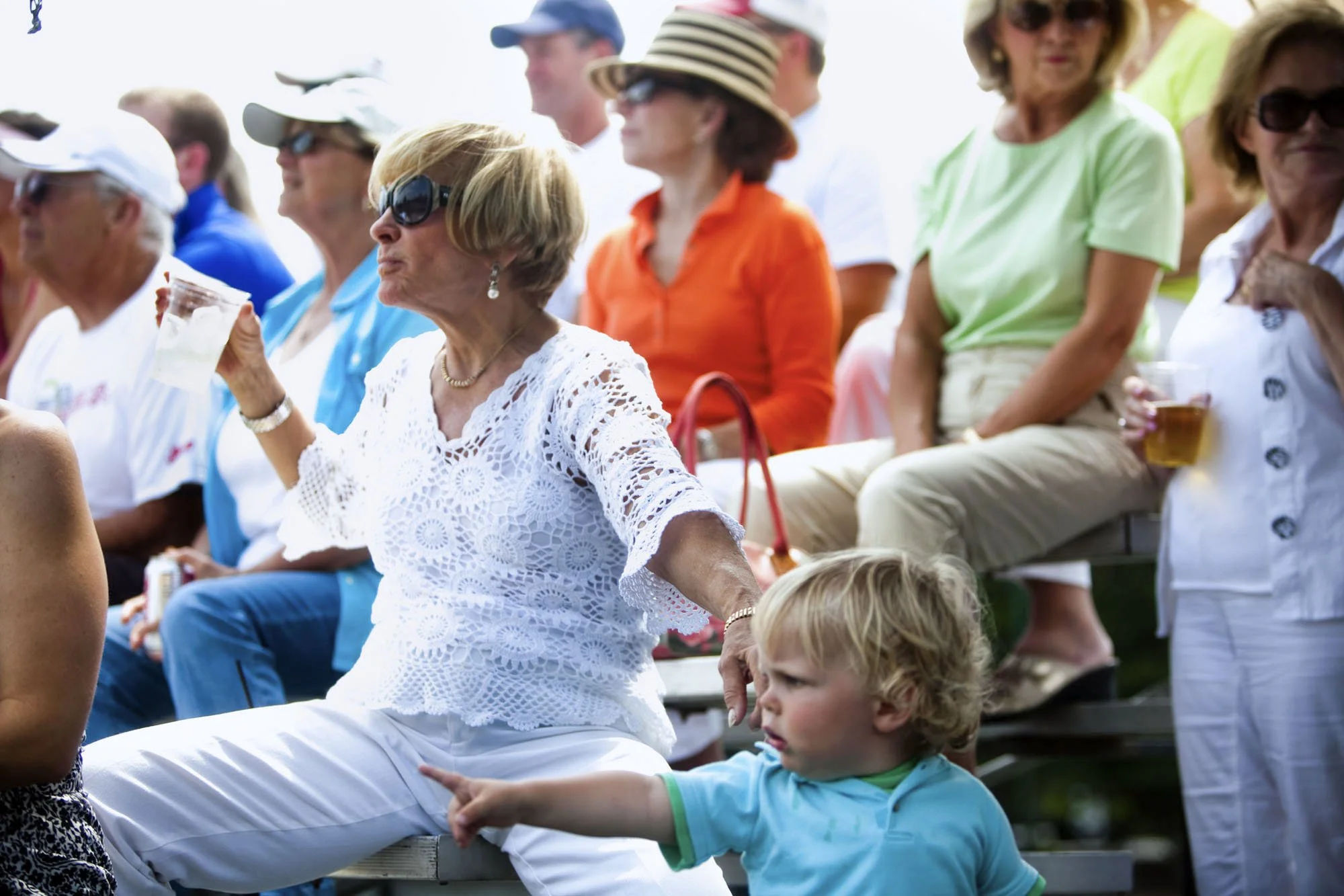 A woman holds her grandson by the collar of his shirt as she watches the Metzger Open singles championship tennis match in Linglestown, Pa.