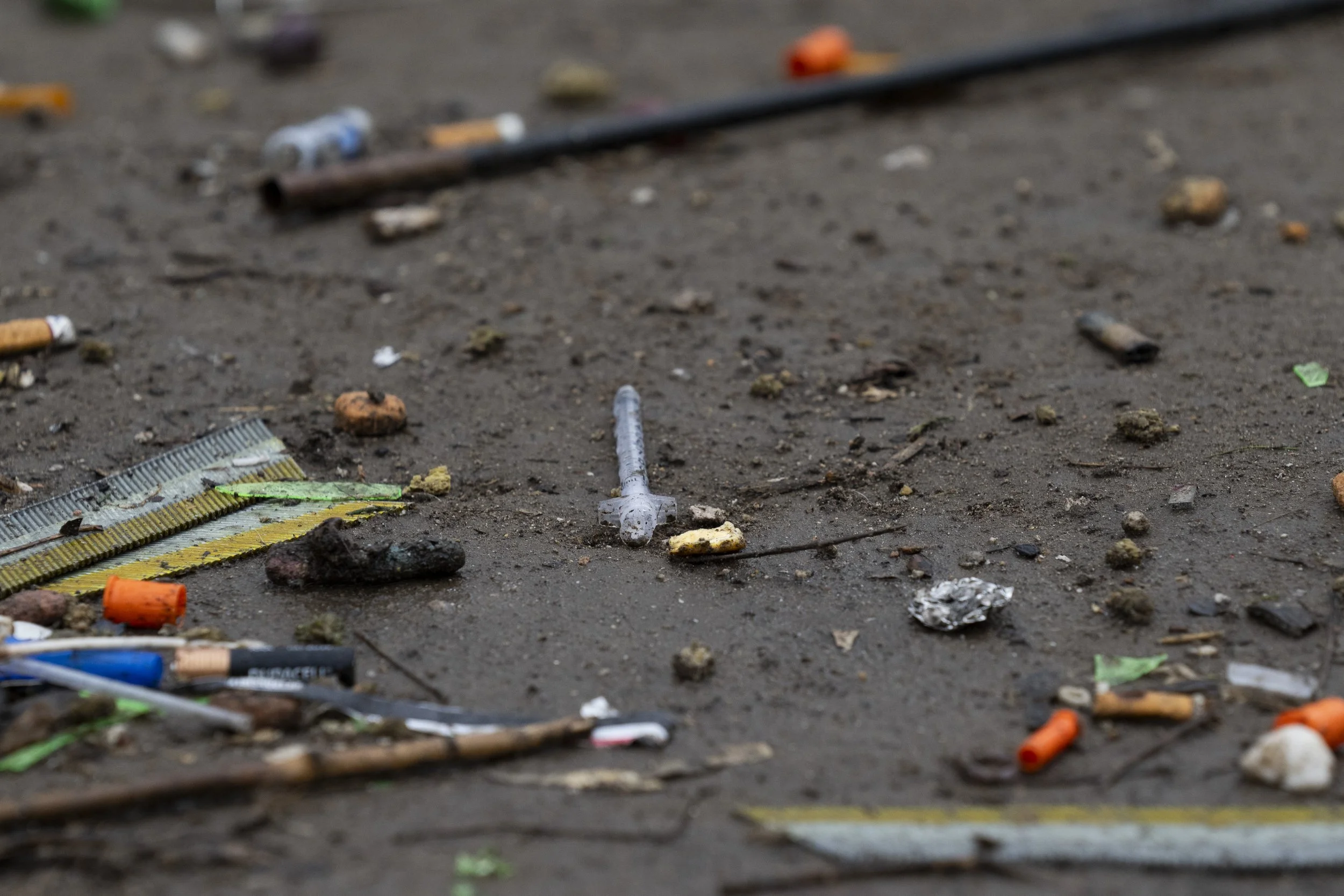 A used needle is seen next to orange syringe caps on the ground on Friday, March 22, 2024, in Baker Park in Grants Pass, Ore. 