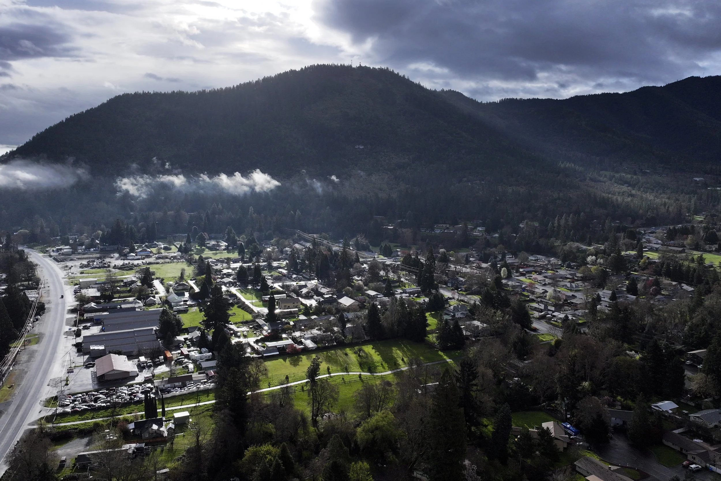 Vehicles drive down Rogue River Highway as light shines on the area March 23, 2024, in Grants Pass, Ore. 