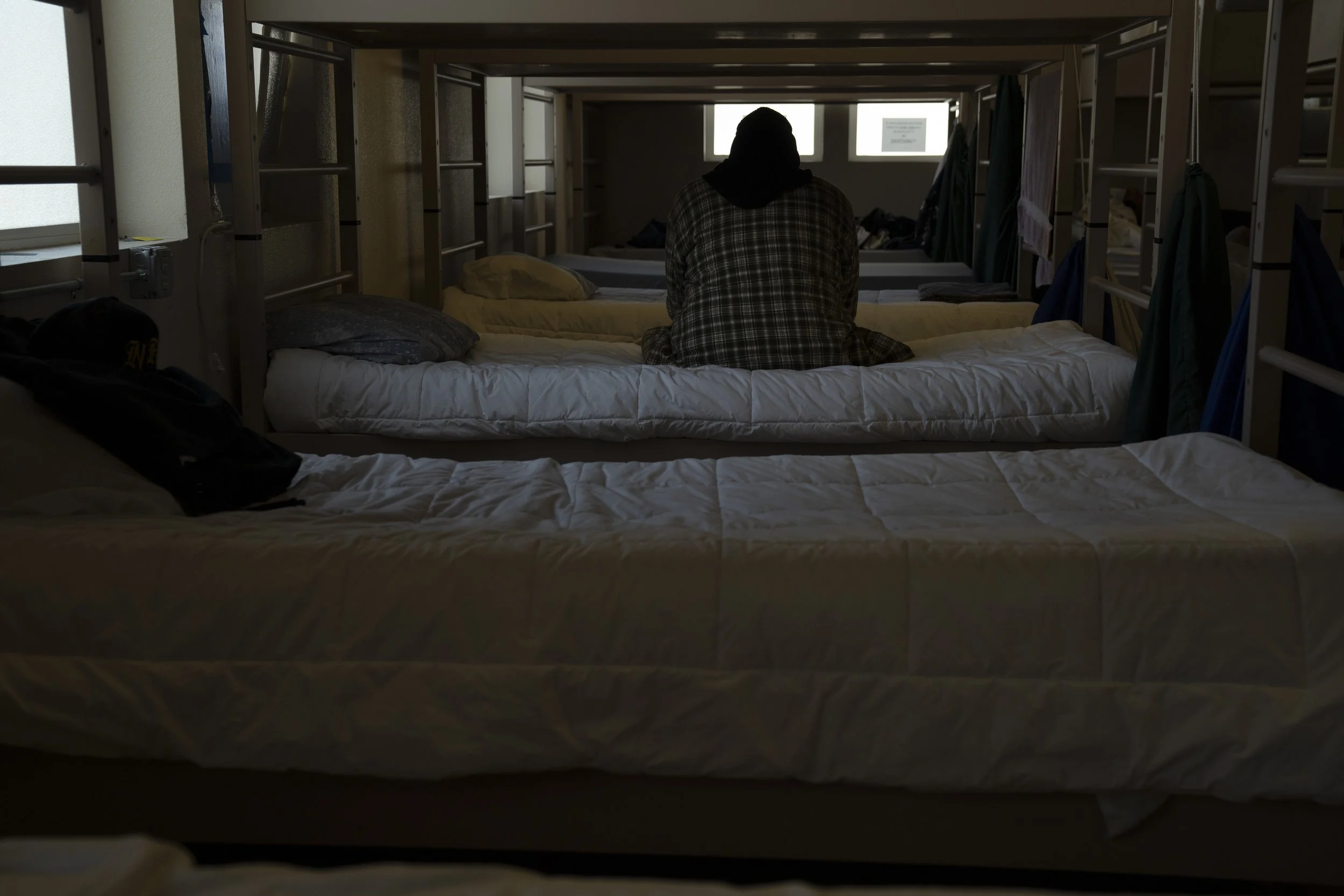 Thomas Person, a resident at the Gospel Rescue Mission, sits on their bed before dinner on Thursday, March 21, 2024, in Grants Pass, Ore. Person arrived at the shelter on March 18. 