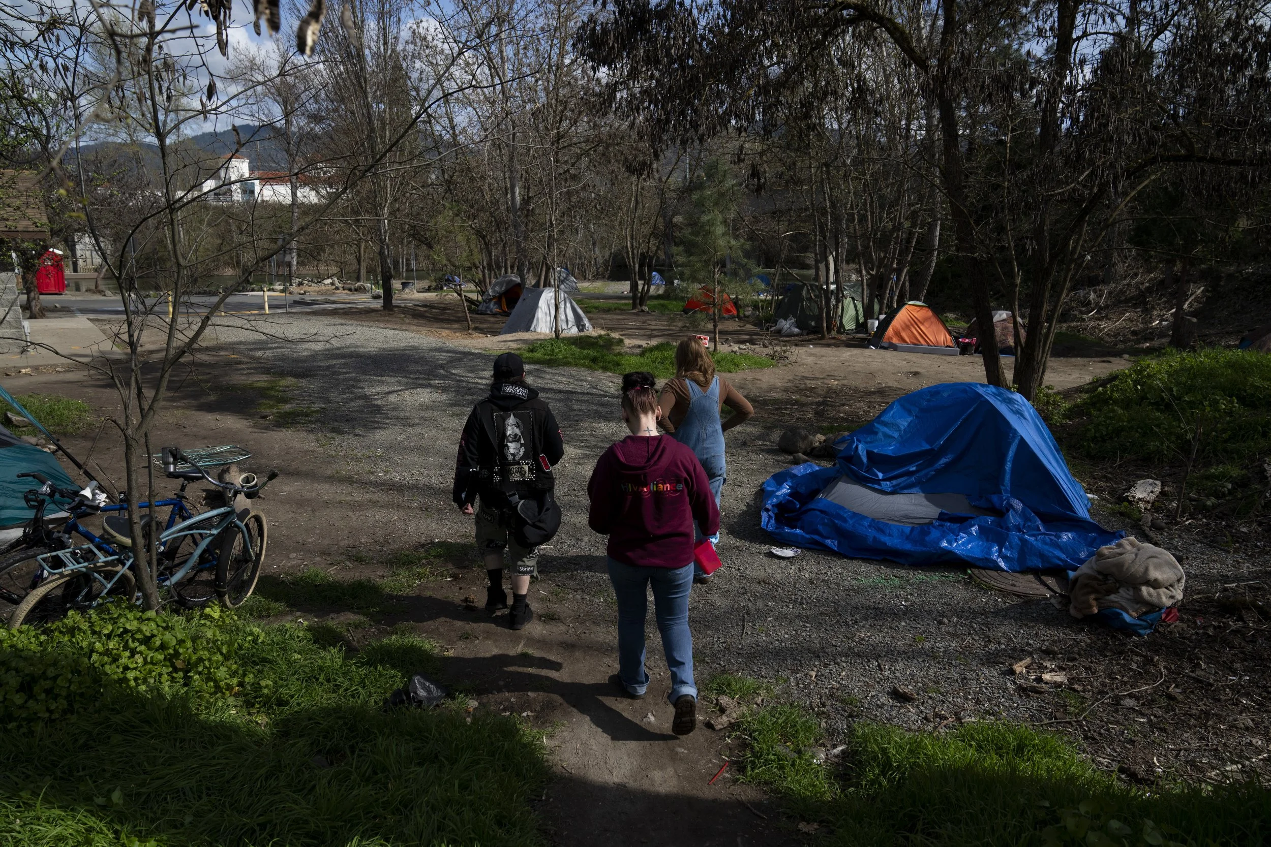 Cassy Leach, a nurse, who leads a group of volunteers who provide food, medical care, and other basic goods to the hundreds of homeless people living in the parks, right, leads a group of volunteers to check on campers in Baker Park on Thursday, Marc