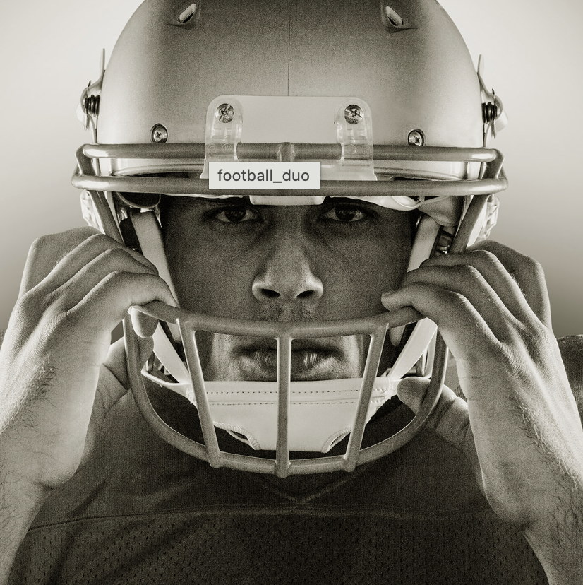 A male football player adjusting his helmet with a serious expression.