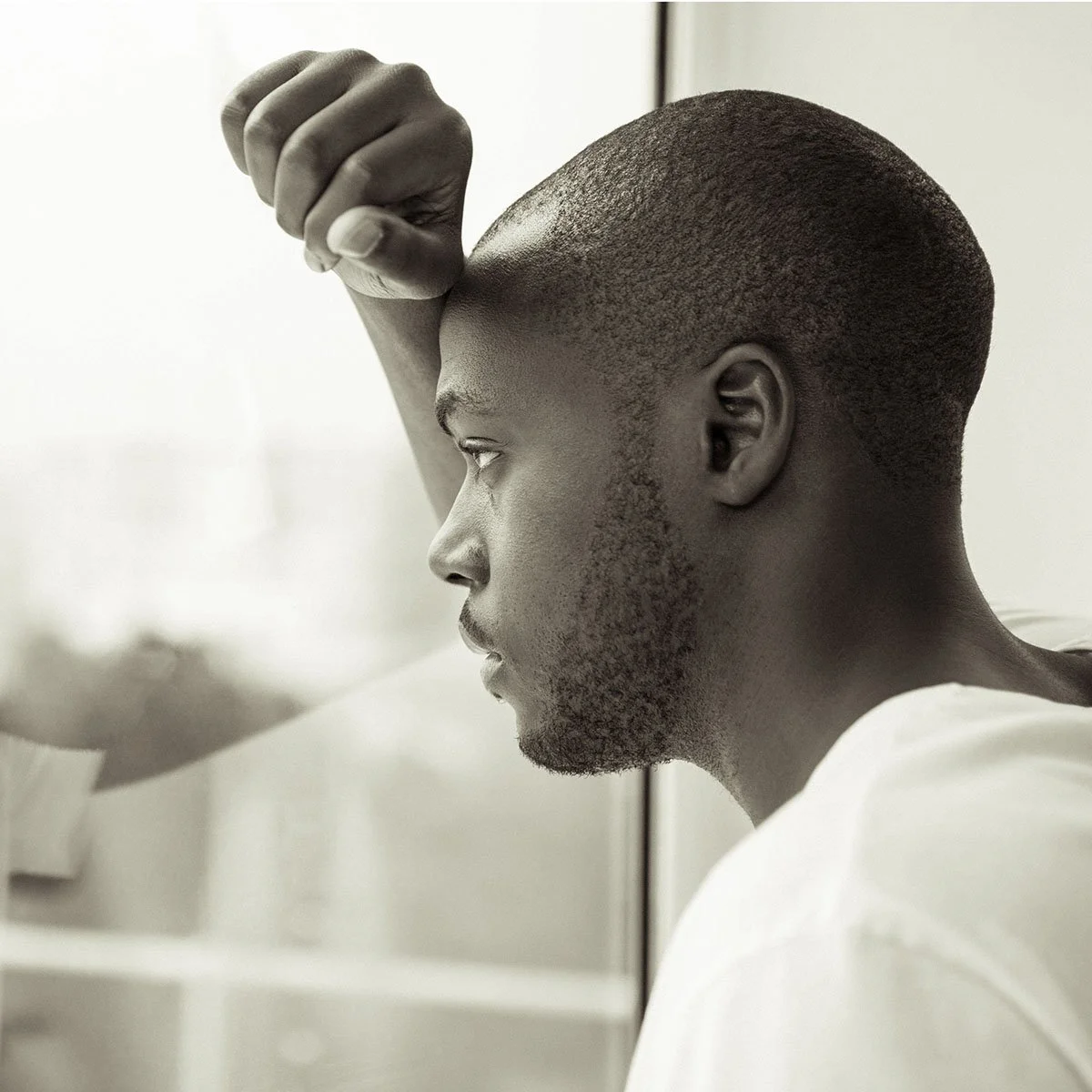 A young man with a shaved head looking to the side, raising his arm with a clenched fist.