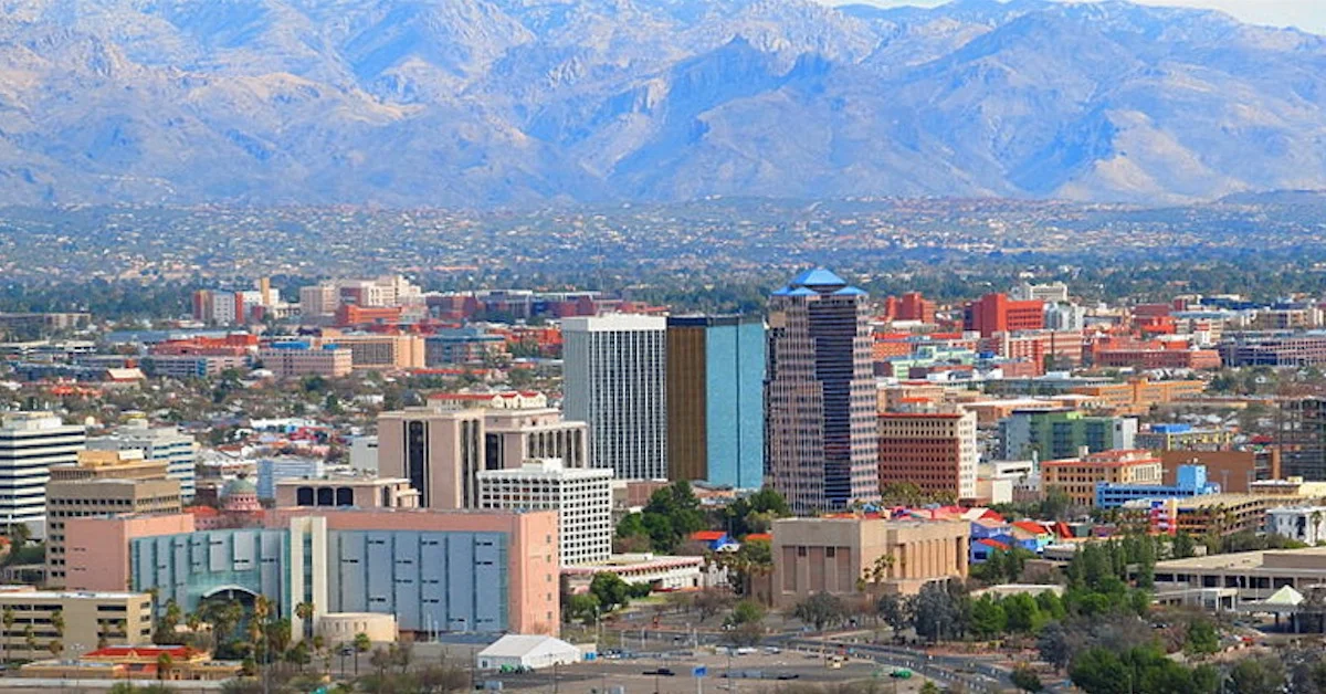 A city skyline with tall buildings and mountains in the background.