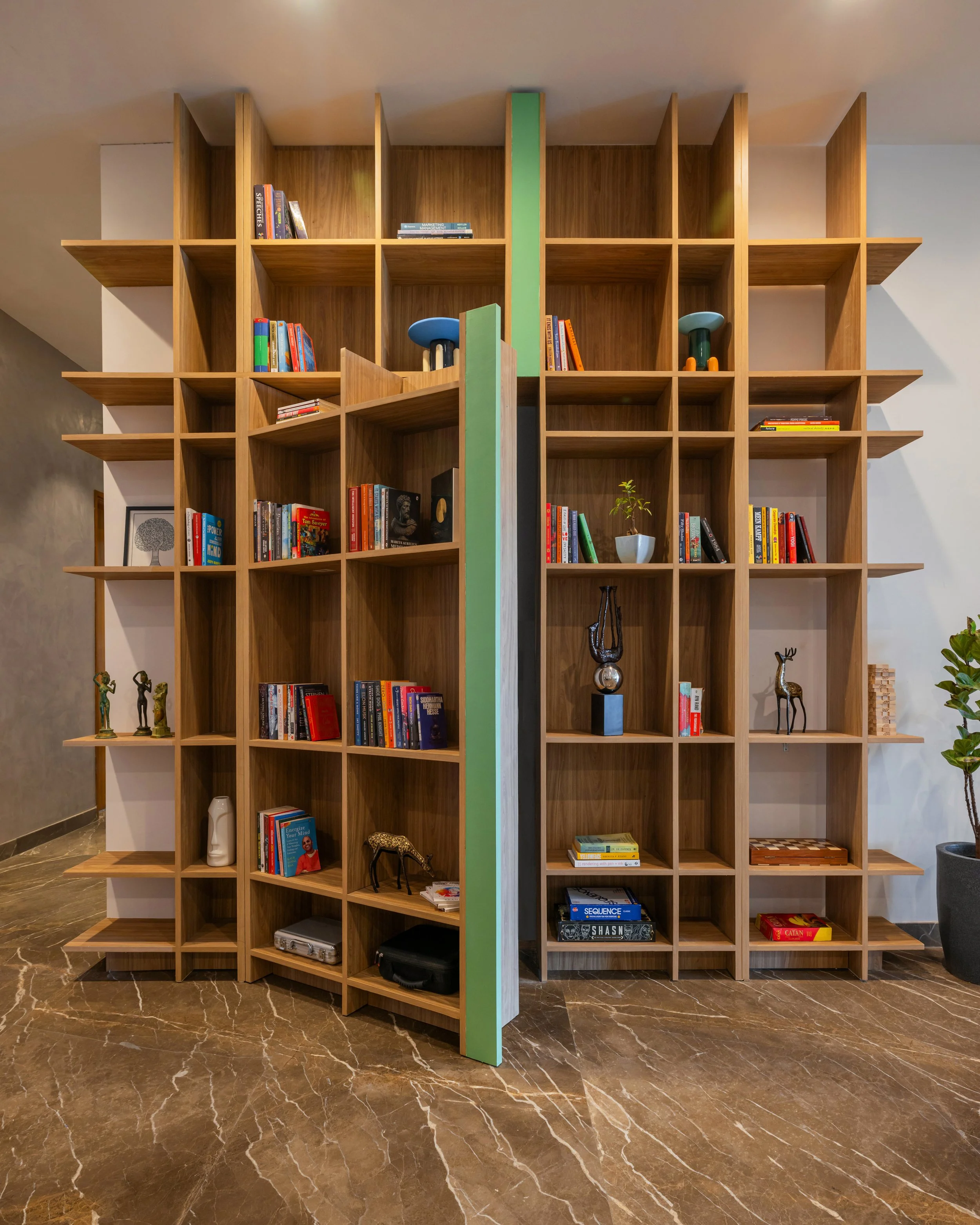 The design is an 11-foot-tall bookshelf that acts as a sculptural feature in the space. At first glance, it appears to be a simple bookshelf, but a closer look reveals that it has two functions, displaying books while concealing the reading nook. Thi