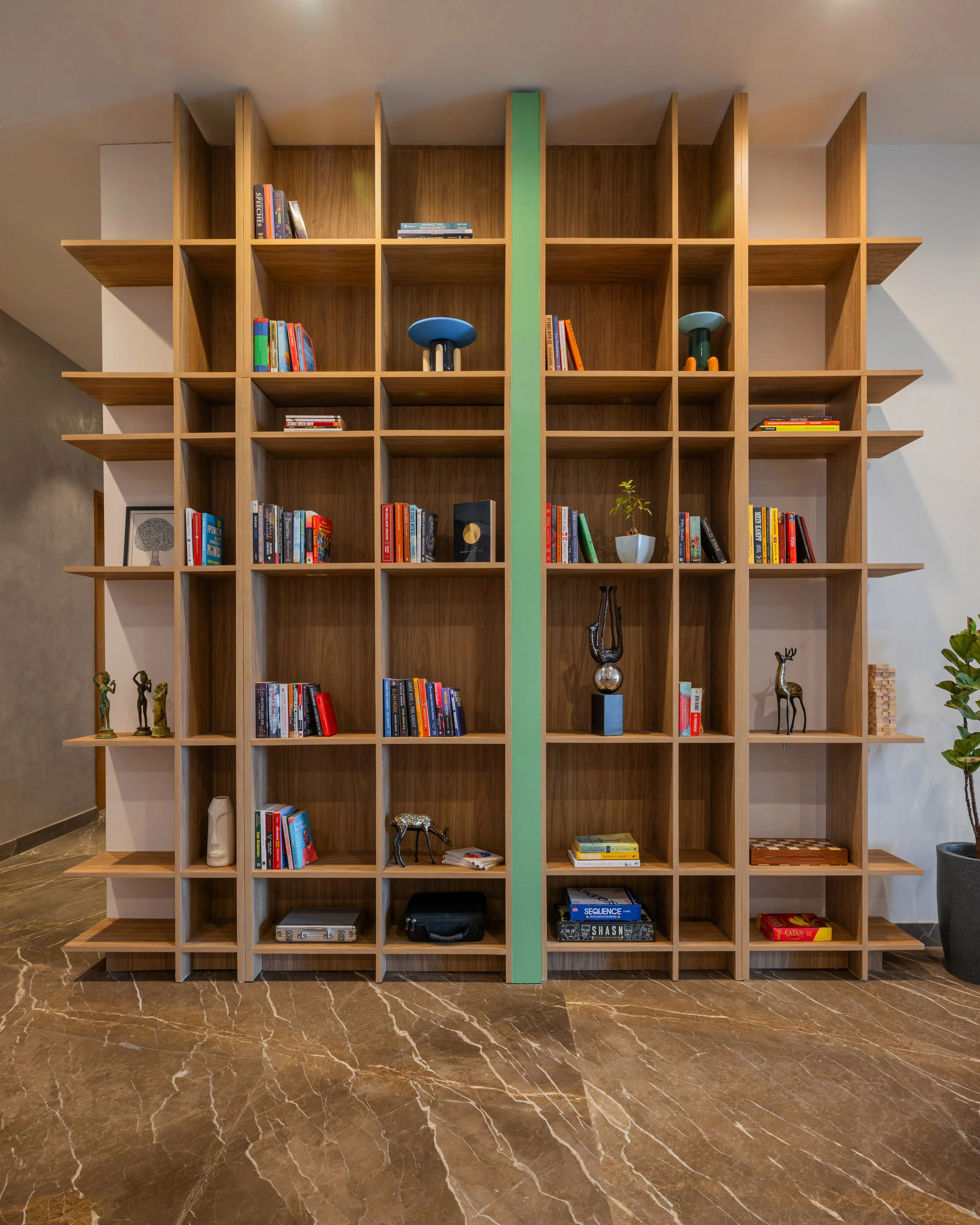 The design is an 11-foot-tall bookshelf that acts as a sculptural feature in the space. At first glance, it appears to be a simple bookshelf, but a closer look reveals that it has two functions, displaying books while concealing the reading nook. Thi