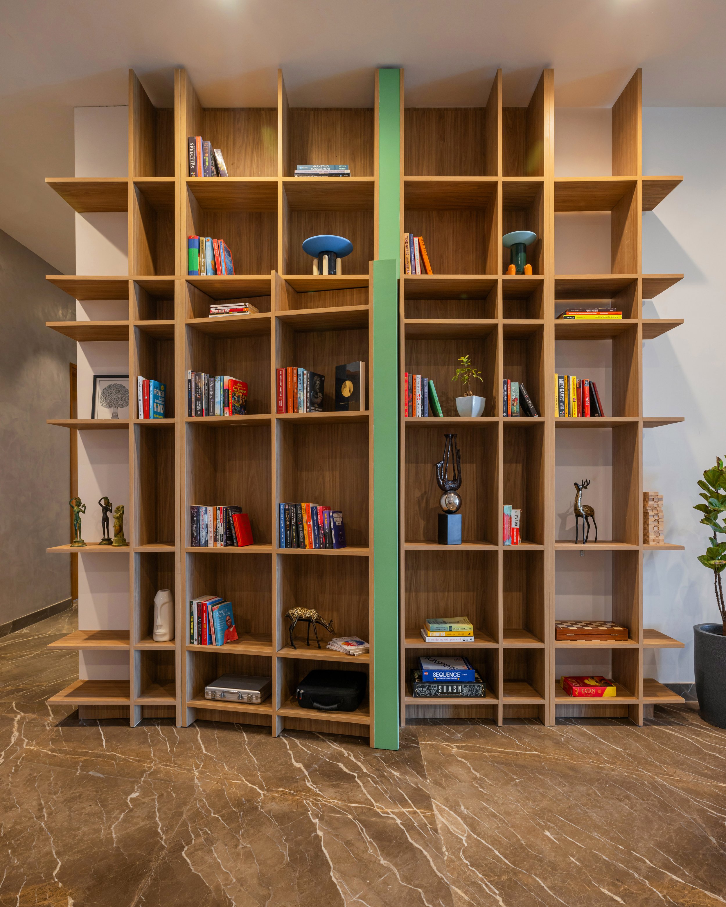 The design is an 11-foot-tall bookshelf that acts as a sculptural feature in the space. At first glance, it appears to be a simple bookshelf, but a closer look reveals that it has two functions, displaying books while concealing the reading nook. Thi