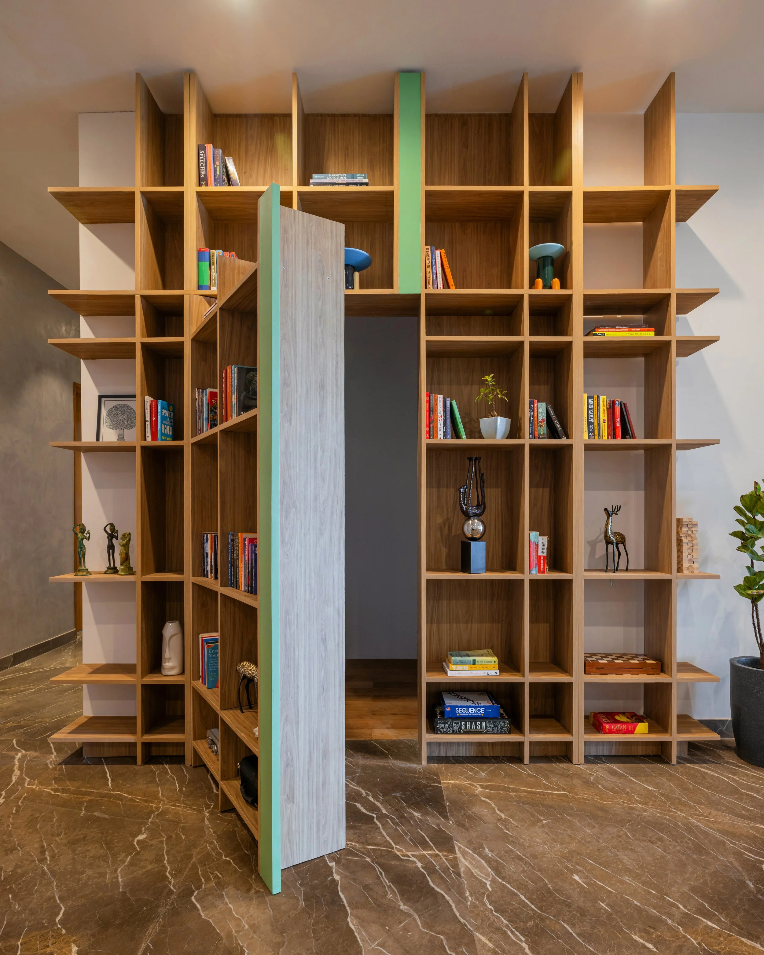 The design is an 11-foot-tall bookshelf that acts as a sculptural feature in the space. At first glance, it appears to be a simple bookshelf, but a closer look reveals that it has two functions, displaying books while concealing the reading nook. Thi