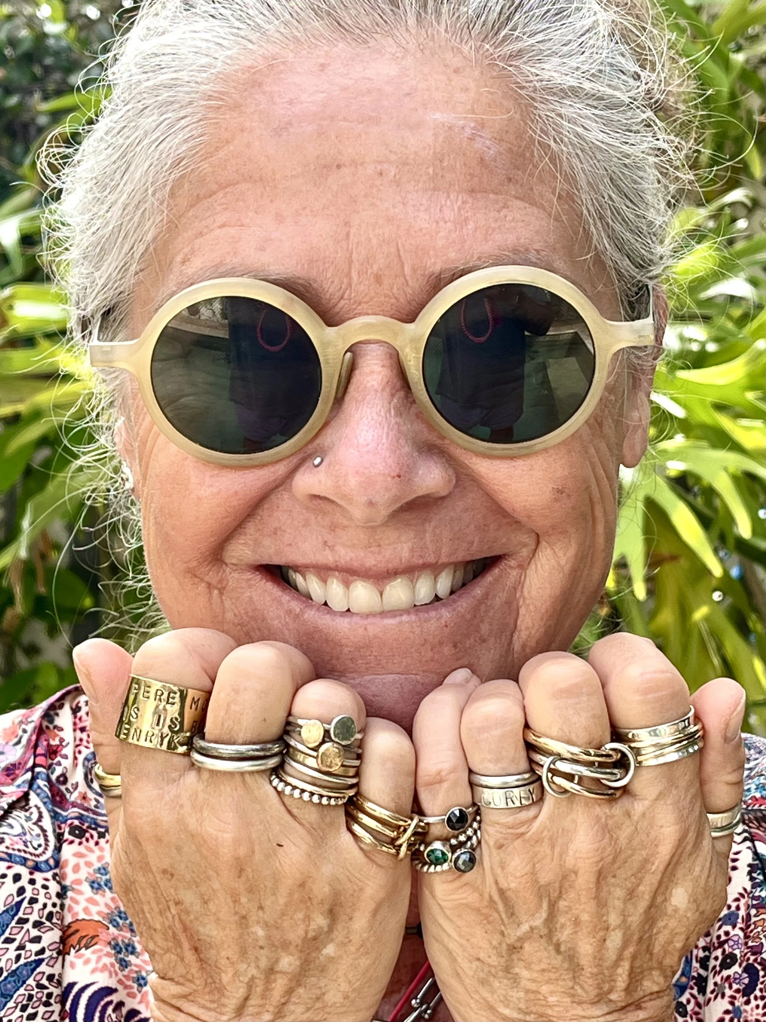 Close-up of a woman with her hands near her face showing multiple rings.