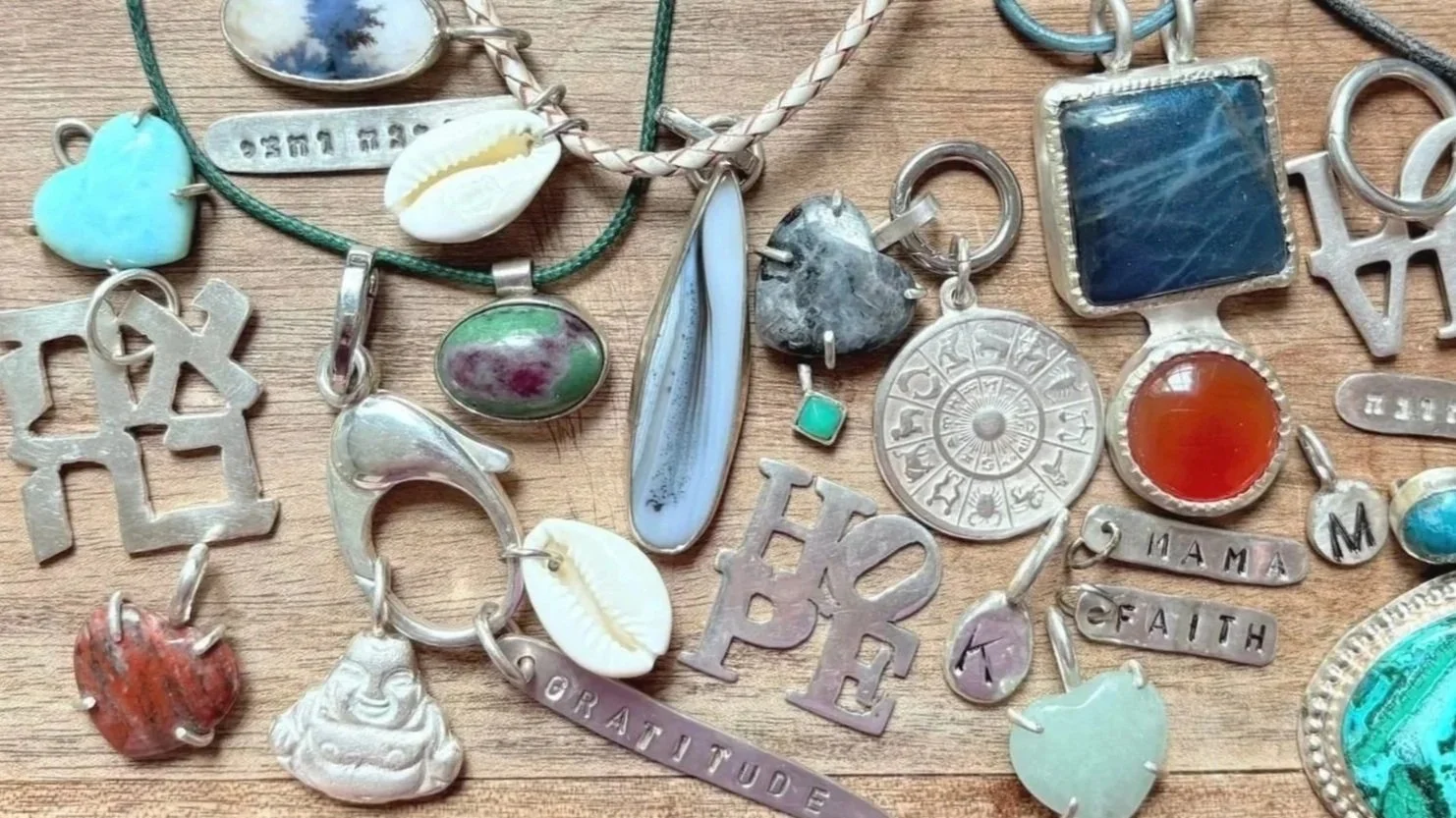 Collection of jewelry and charms on a wooden surface, including shells, stones, and metal pendants.
