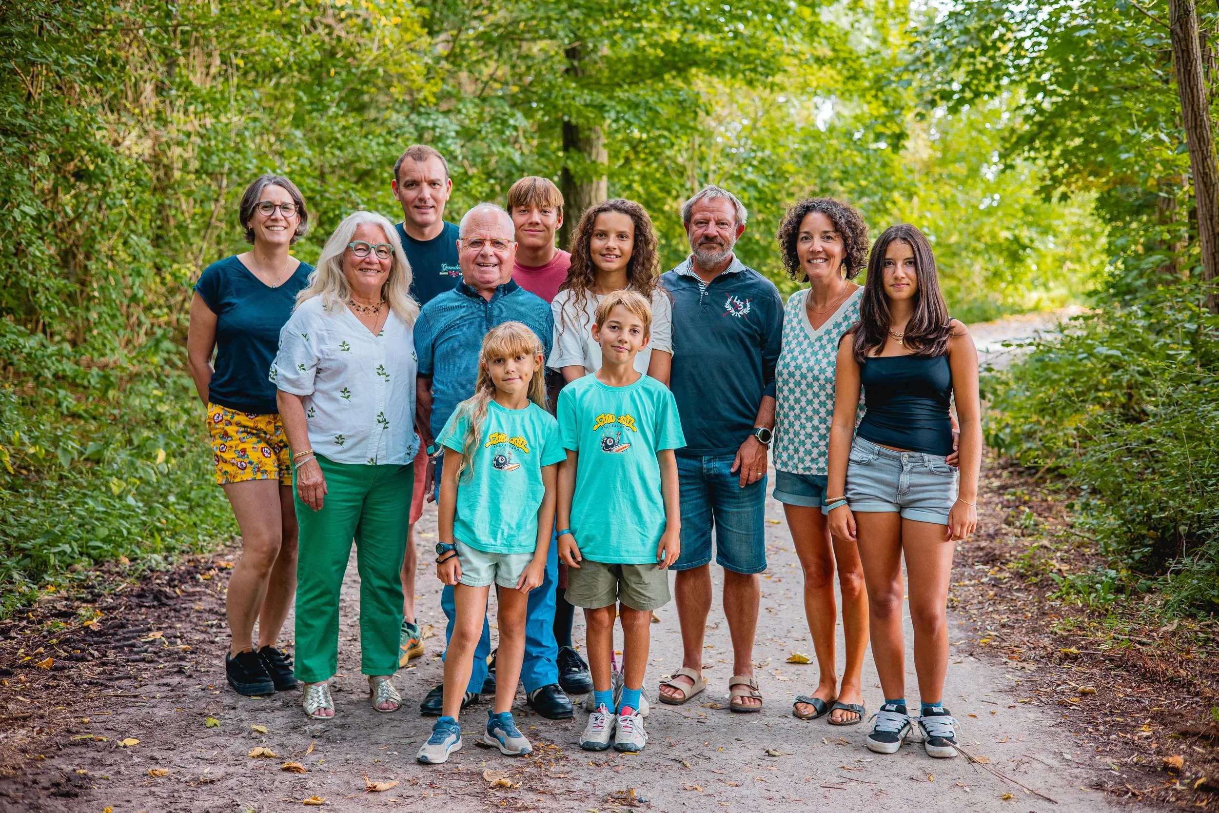 Un groupe de personnes de différents âges posent sur un sentier dans une forêt verdoyante.