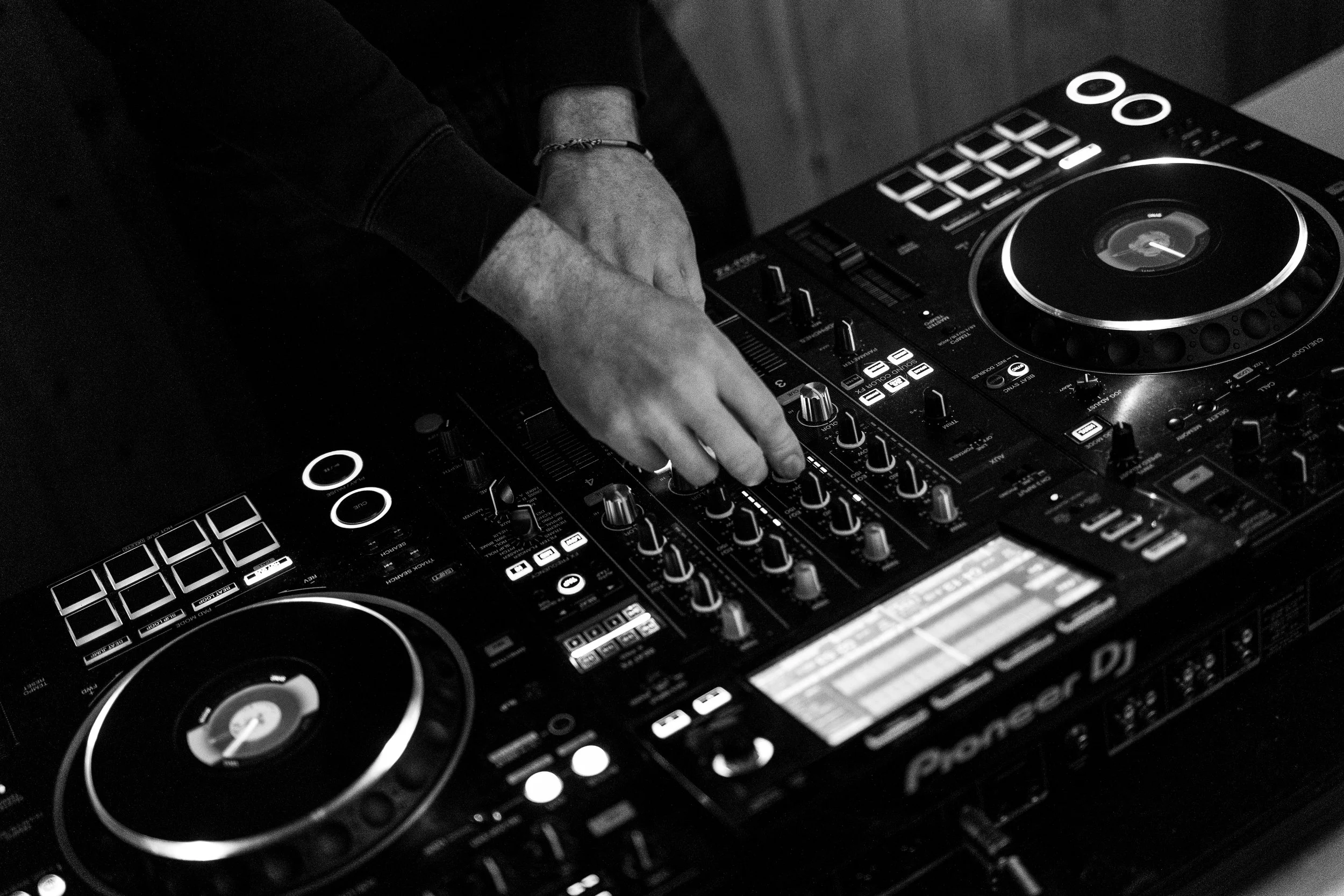 Un DJ manipule un contrôleur de musique en noir et blanc.