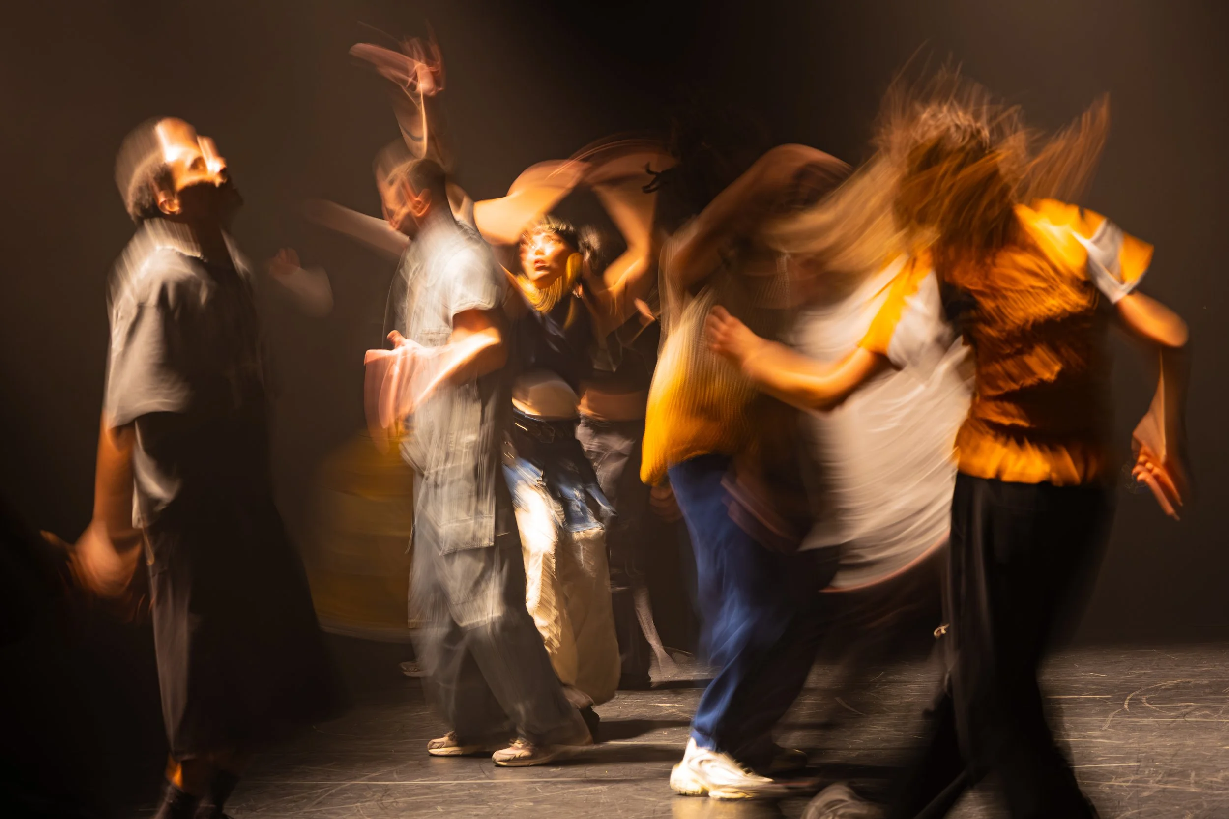 Groupe de personnes en mouvement dansant, éclairage chaud, flou artistique.