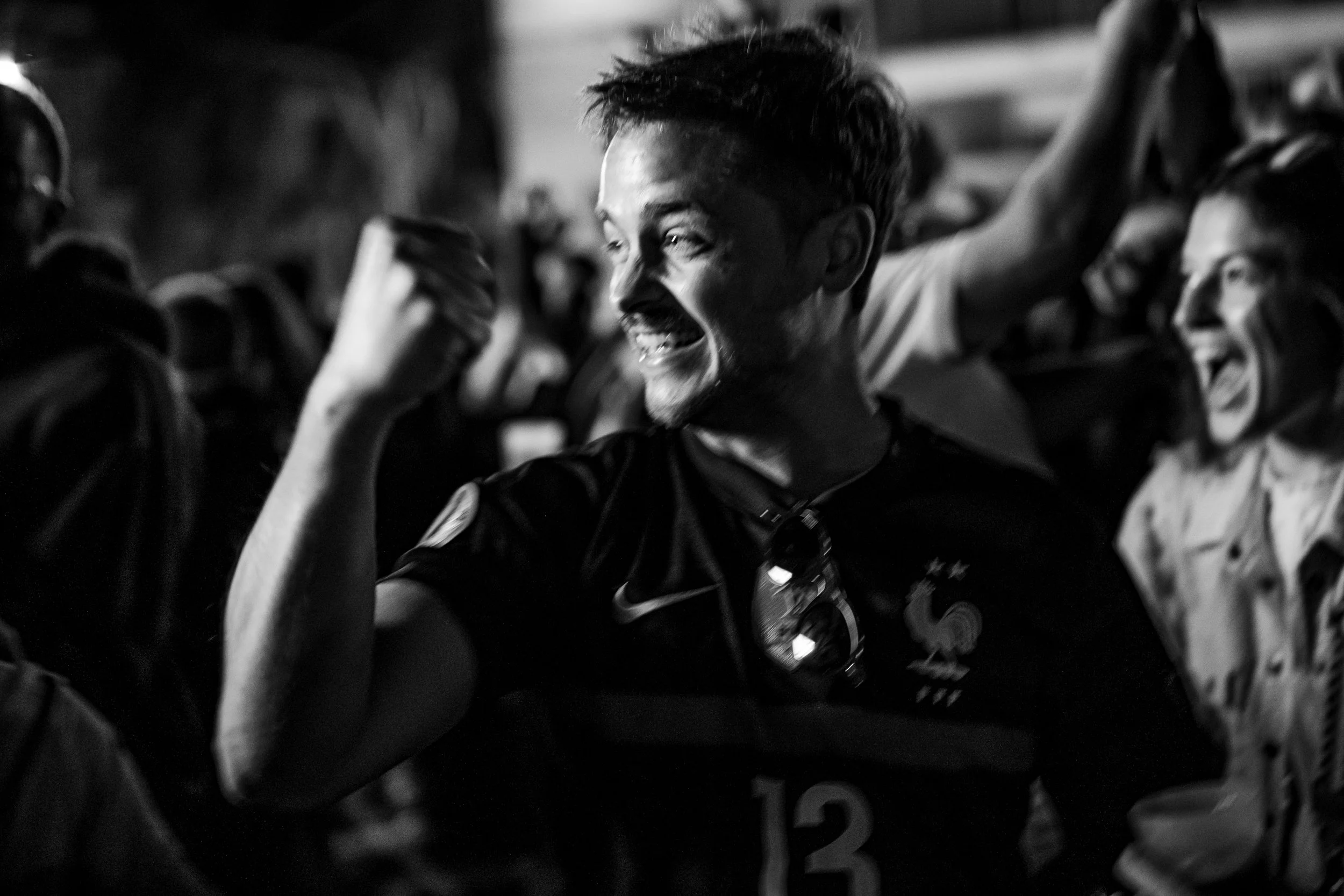 Un homme souriant dans un groupe, en haut de son uniforme de sport avec médailles, en noir et blanc.