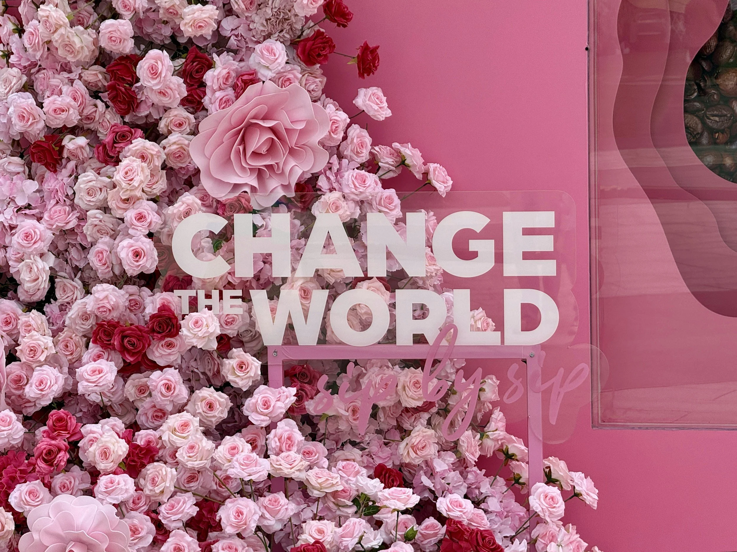 Pink and red roses arranged on a wall next to a pink sign with the word 'CHANGE' visible.