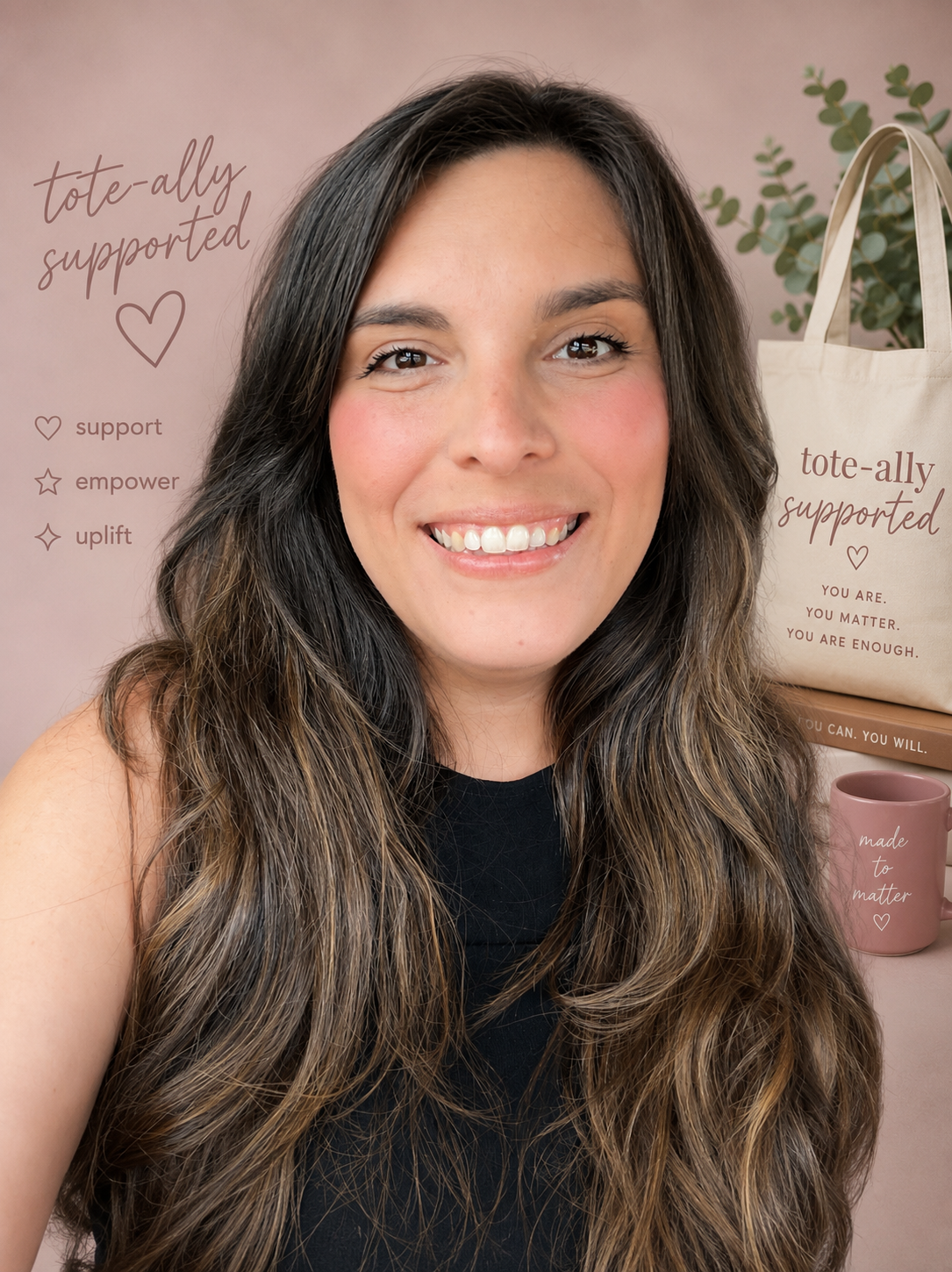 A woman with long wavy brown hair smiling in front of a pink background with supportive tote bags, a pink mug, and a plant.