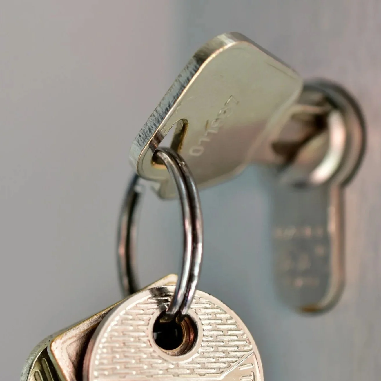 Close-up of a metal key with a keychain hanging from a silver lock.