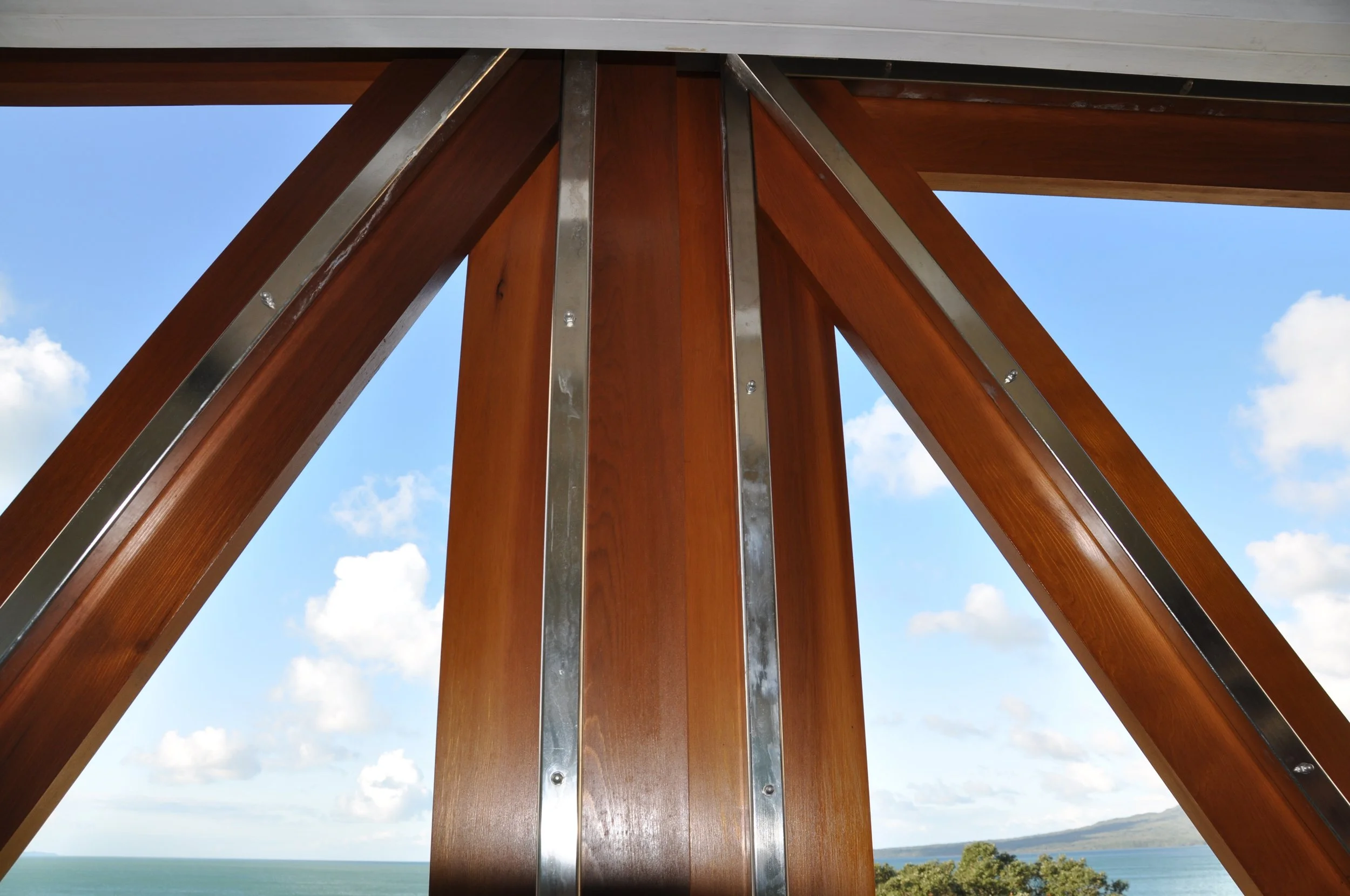 Close-up of a wooden and metal structure against a blue sky with clouds and a distant landscape.