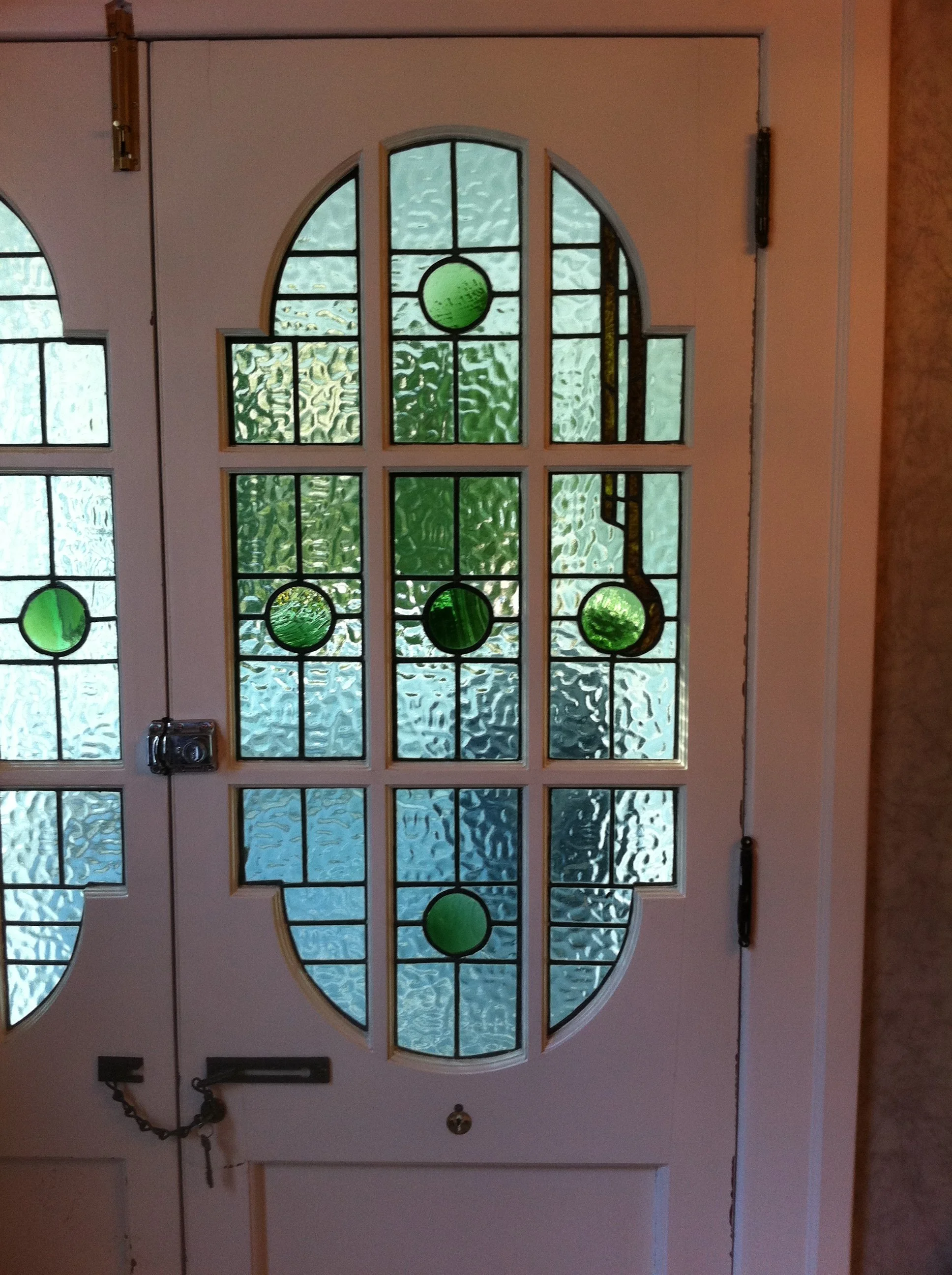 Front view of a white door with decorative stained glass window featuring circular and rectangular green and textured glass panels.