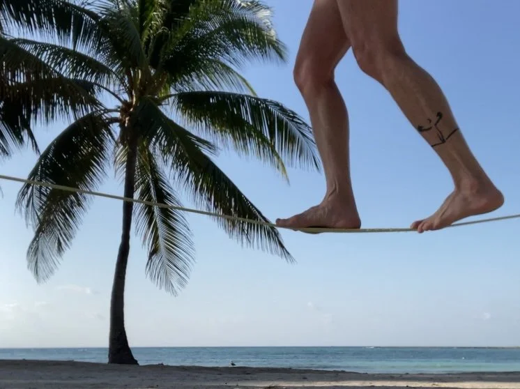 Rae Raptor’s feet on slackline with palm trees