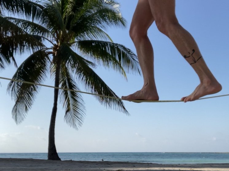 Rae Raptor’s feet on slackline with palm trees