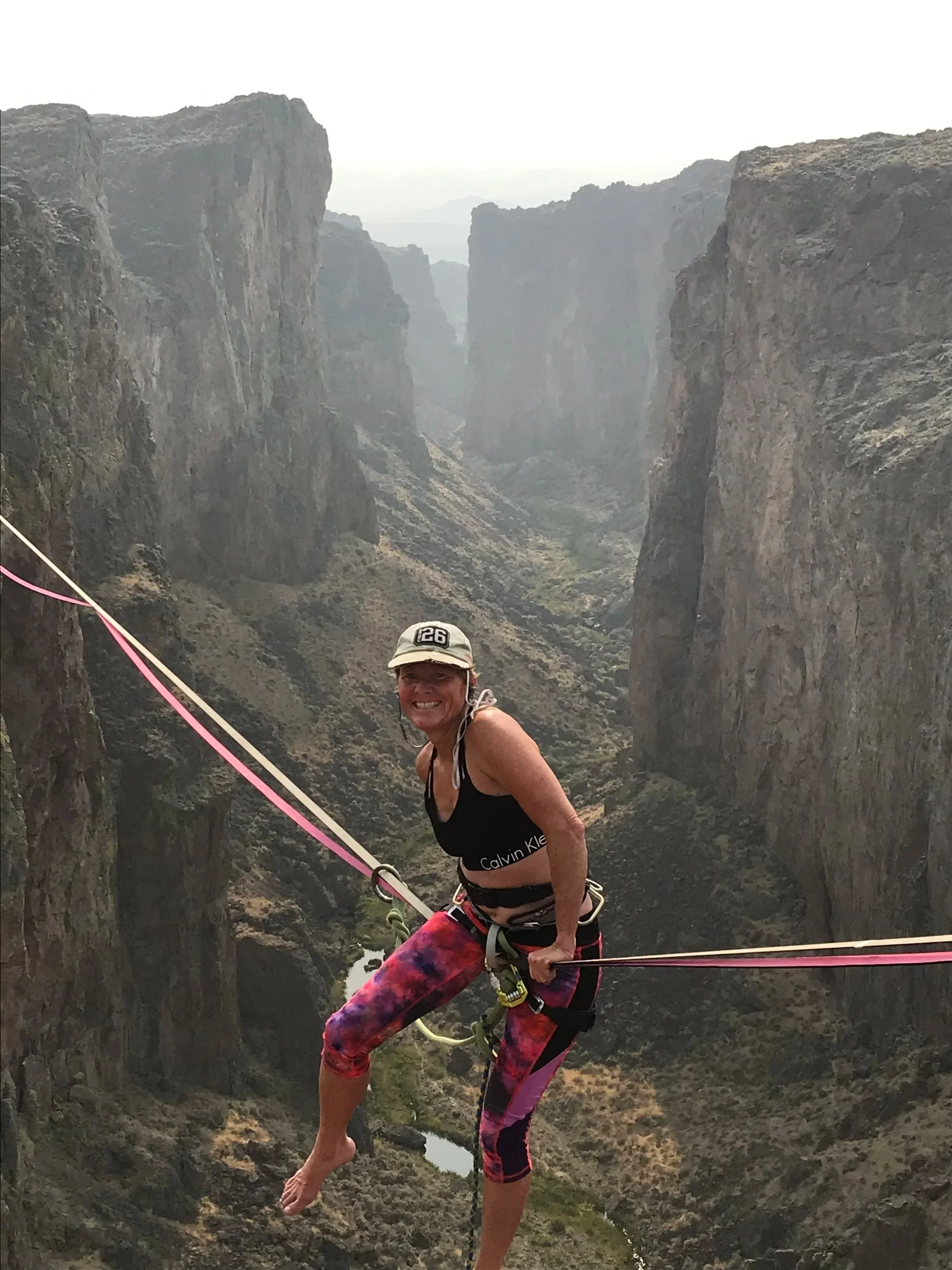 Woman sits on highline above deep valley
