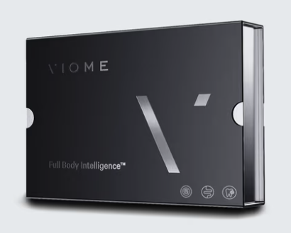 Black rectangular box containing a V-shaped logo, with the text 'V·HOME' and 'Full Body Intelligence™' on the front.