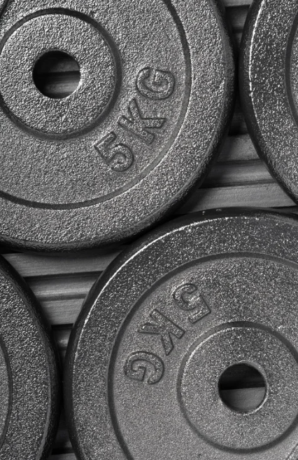 Close-up of two black rubber-coated weight plates, each marked with '5 KG'.