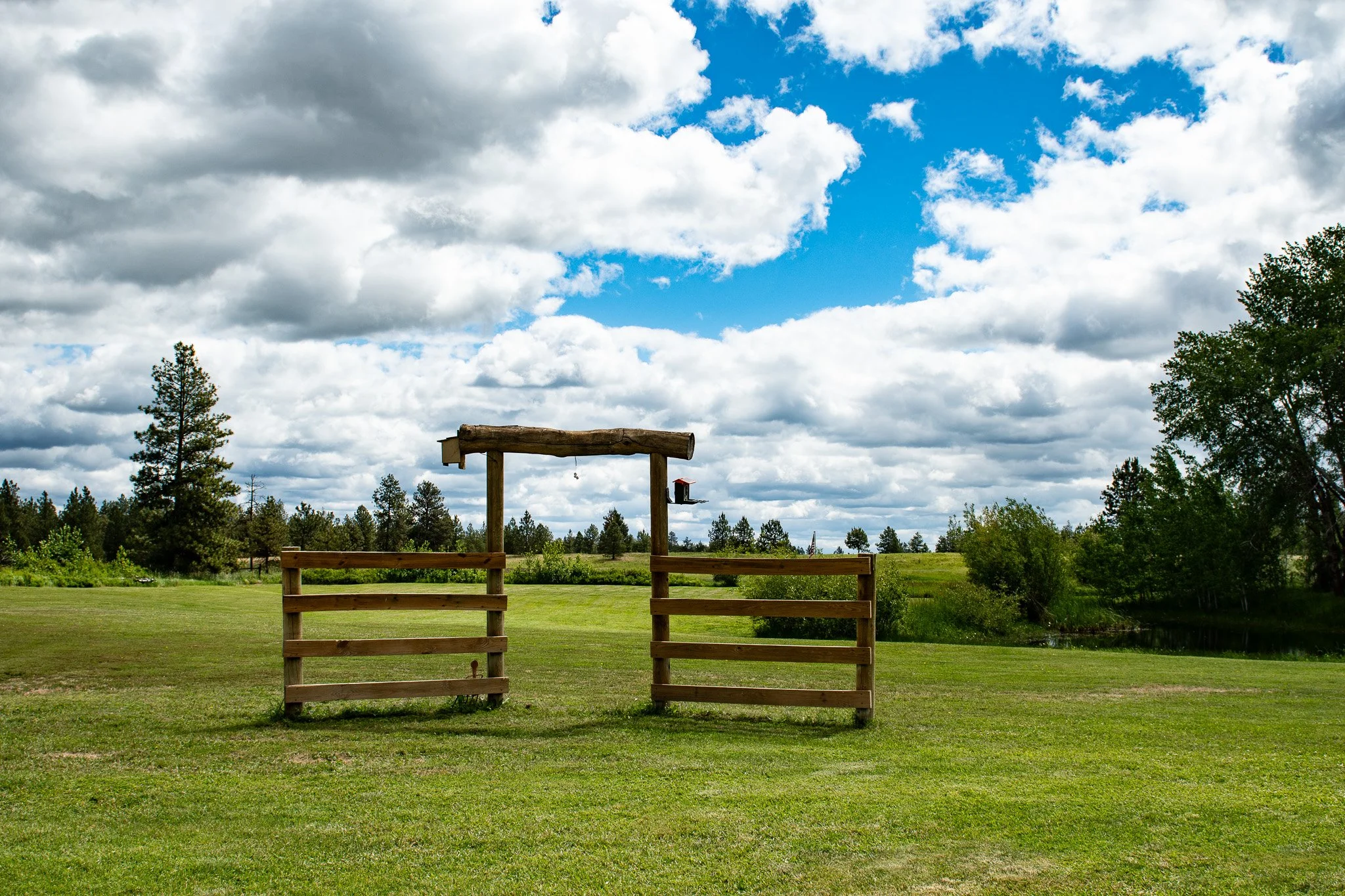 wood archway on farm with trees blue sky and clouds