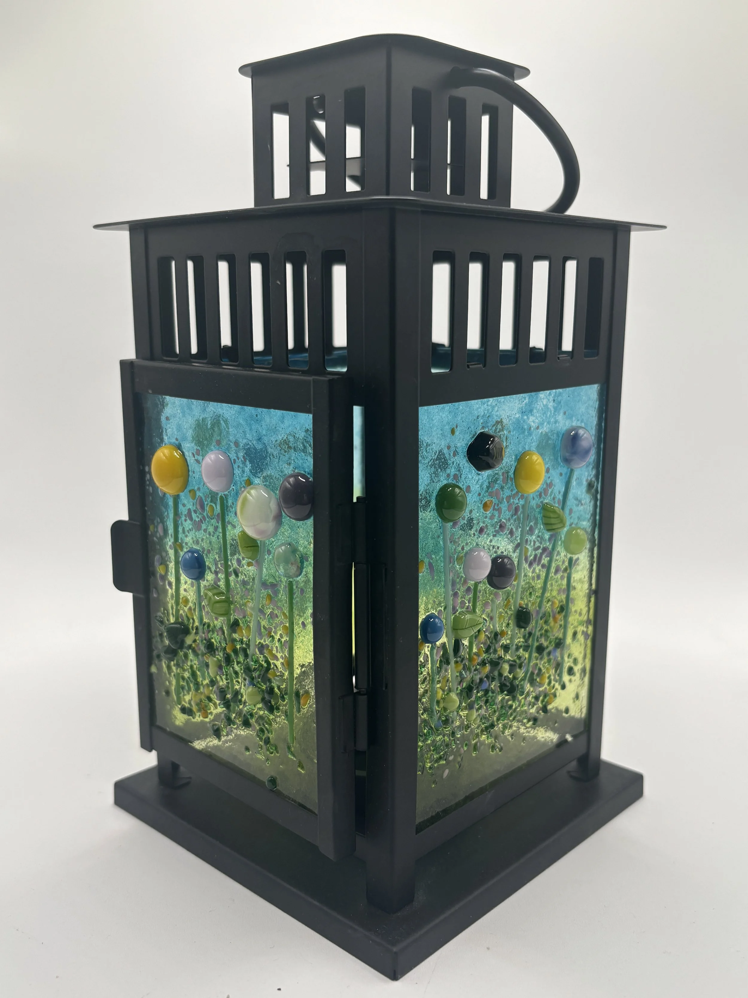 A black plastic lighthouse-shaped container filled with colorful marbles and a green aquatic scene on its side, against a white background.