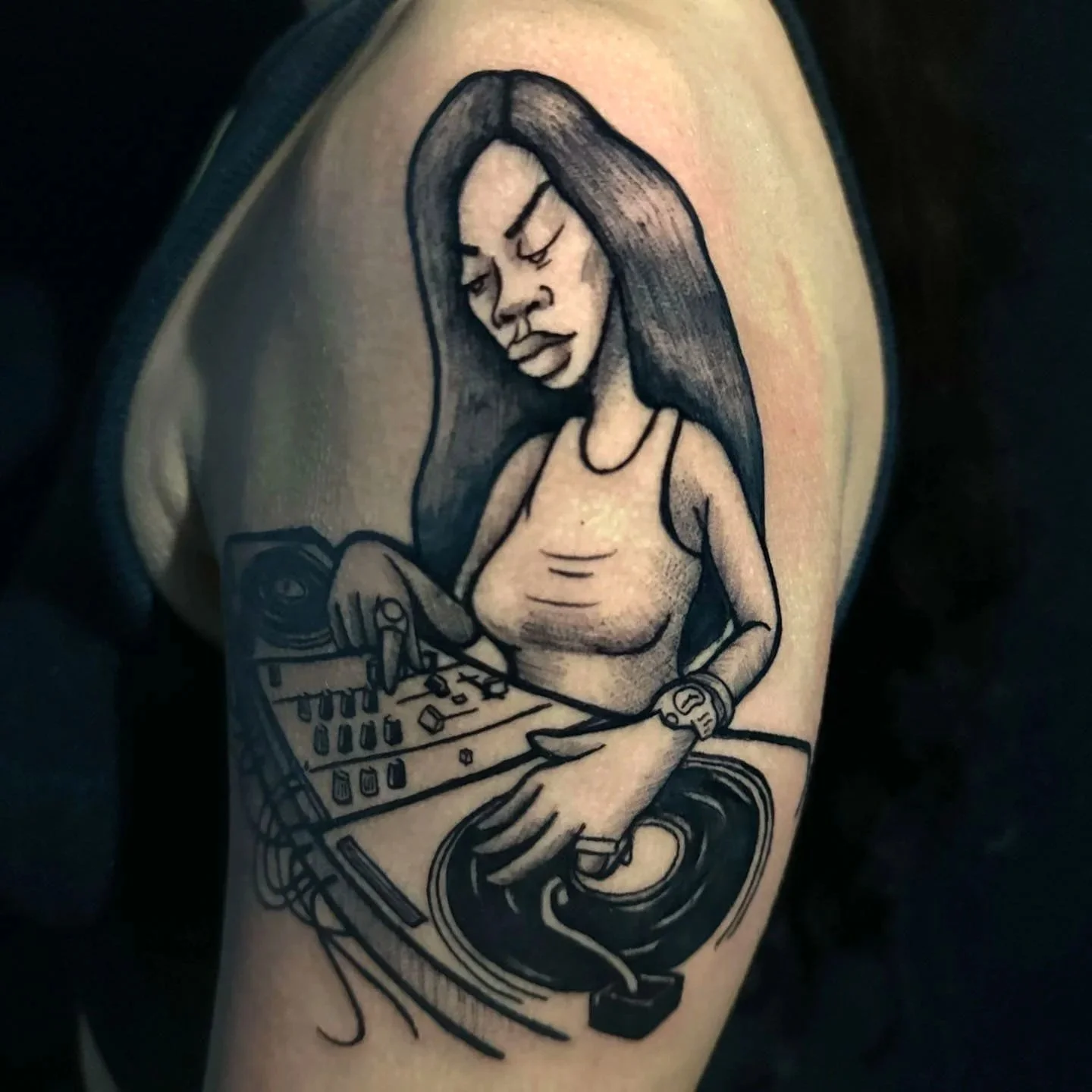 Black line tattoo of a woman with long hair, closed eyes, and a serious expression, wearing a tank top and a watch, operating DJ equipment with one hand on a turntable and the other on a mixer.