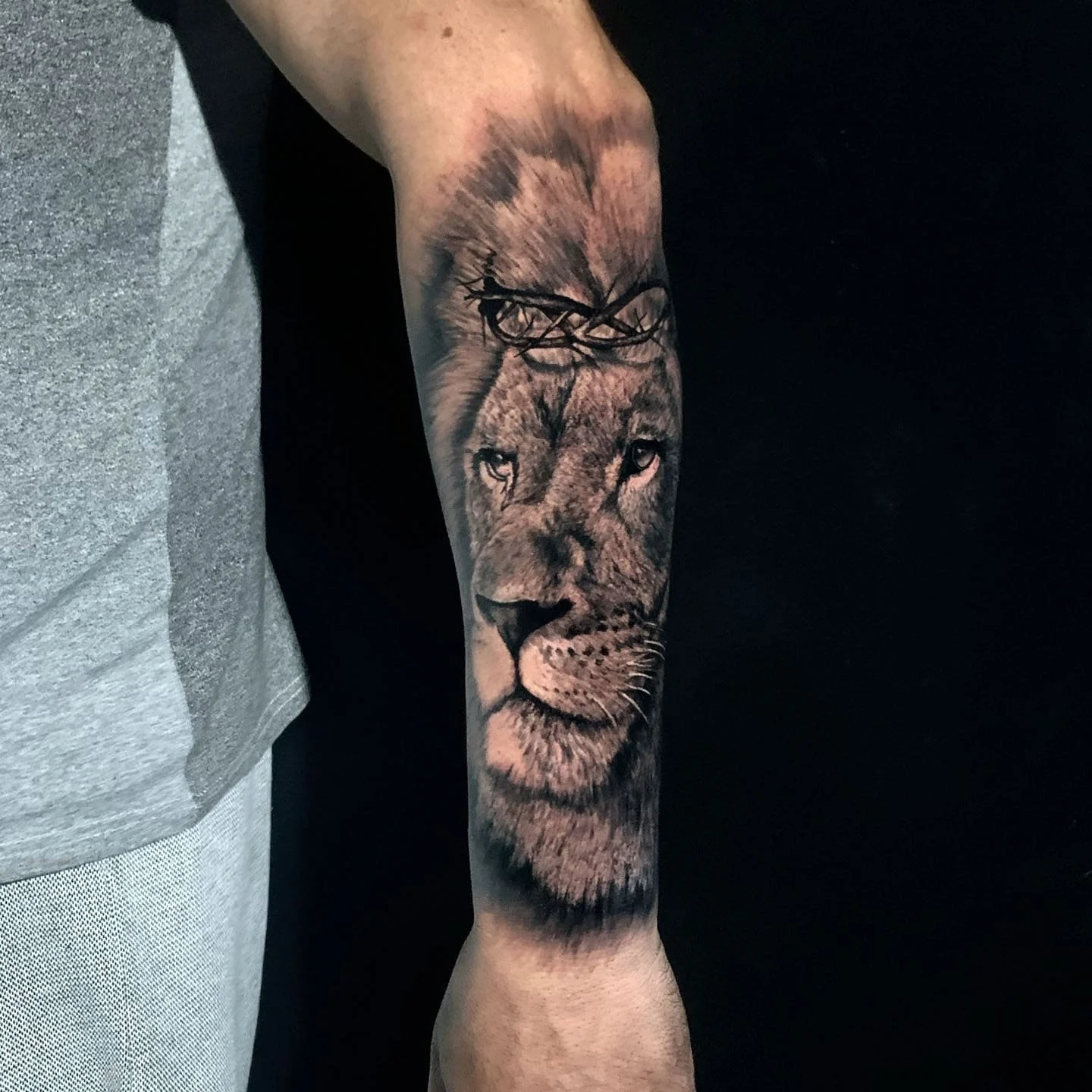 Tattoo of a lion's face on a person's forearm.