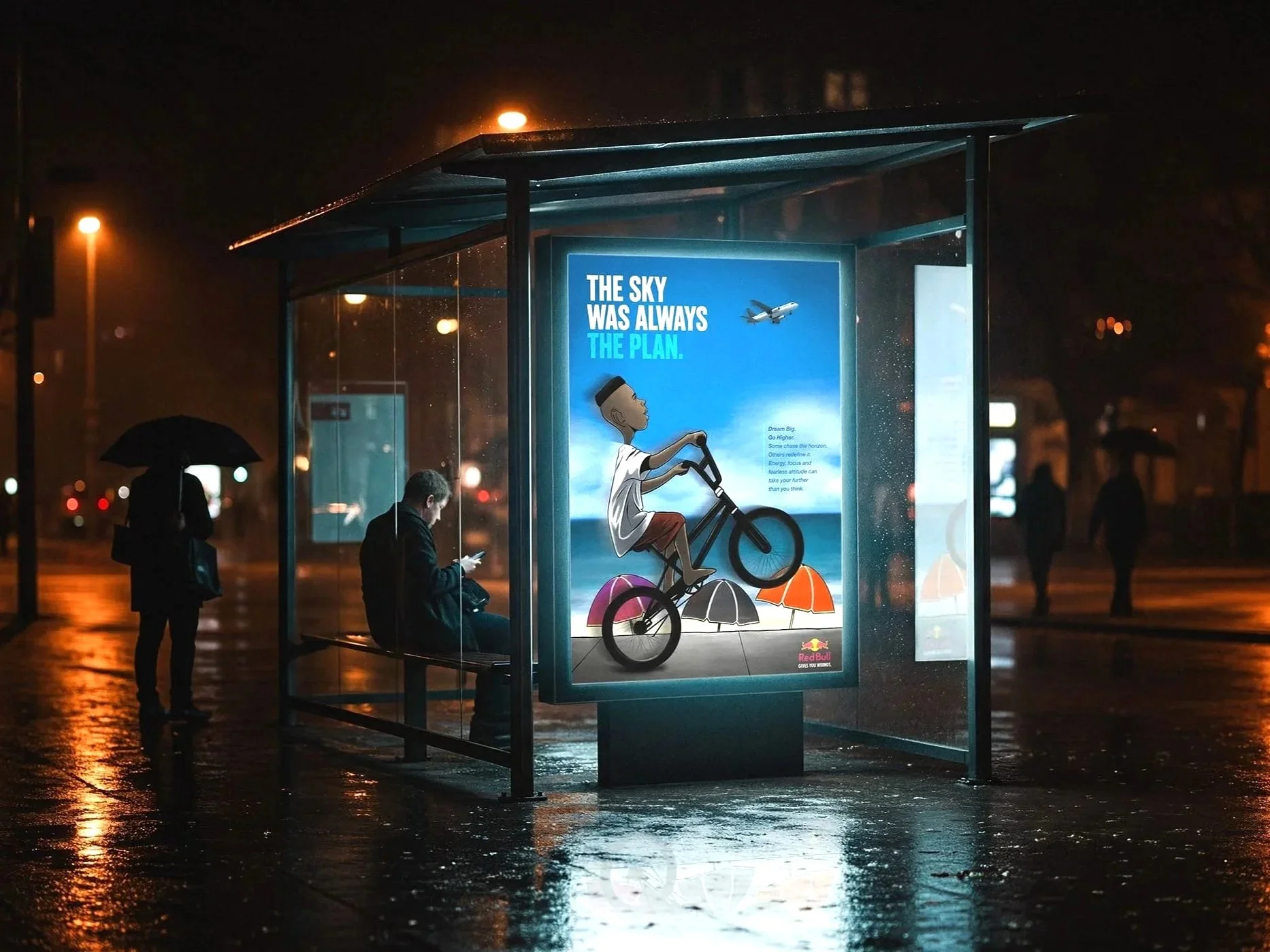 A bus stop shelter at night with rain on the ground. Inside the shelter is a brightly lit advertisement featuring a cartoon person riding a bicycle with umbrellas and the text "The sky was always the plan". There are a few people around, one sitting inside the shelter looking at their phone, and another standing outside holding an umbrella.