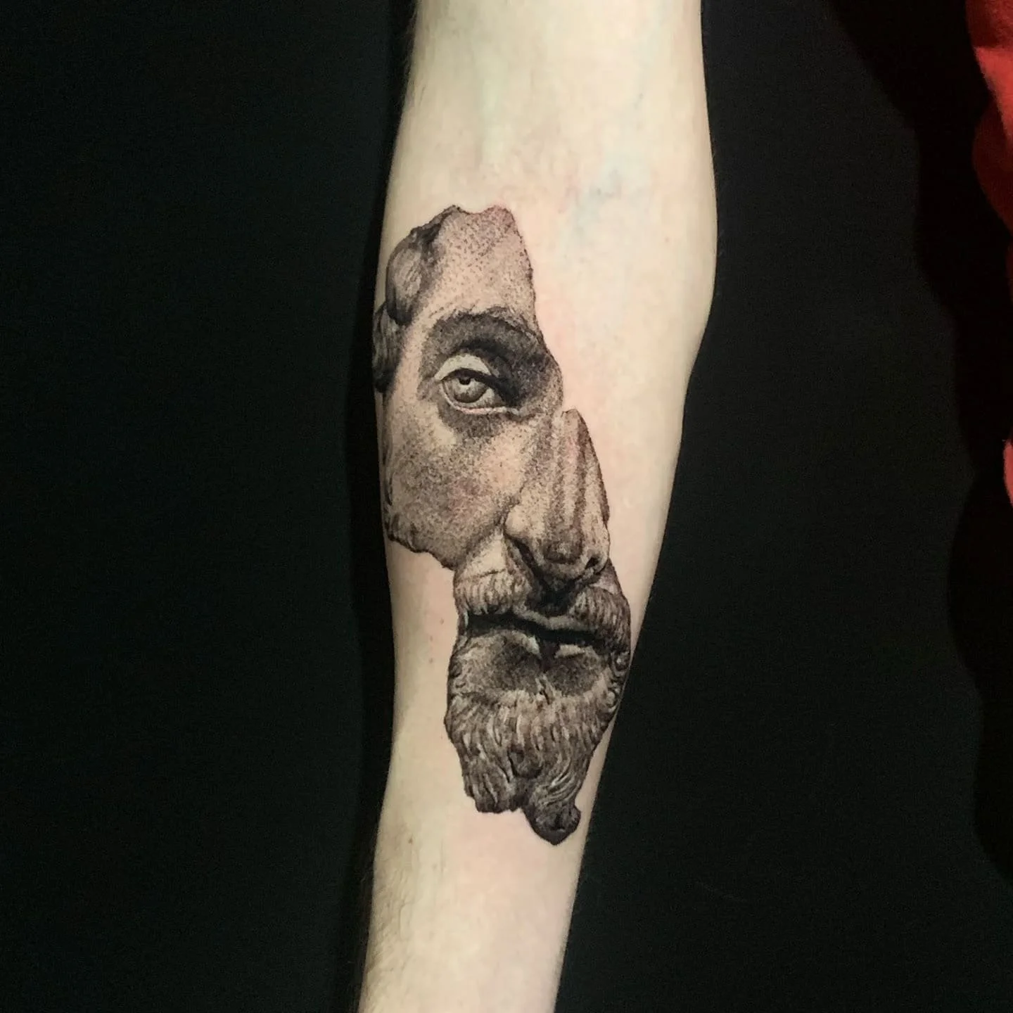 Tattoo of a detailed, realistic man's face with a beard and mustache on a person's forearm.