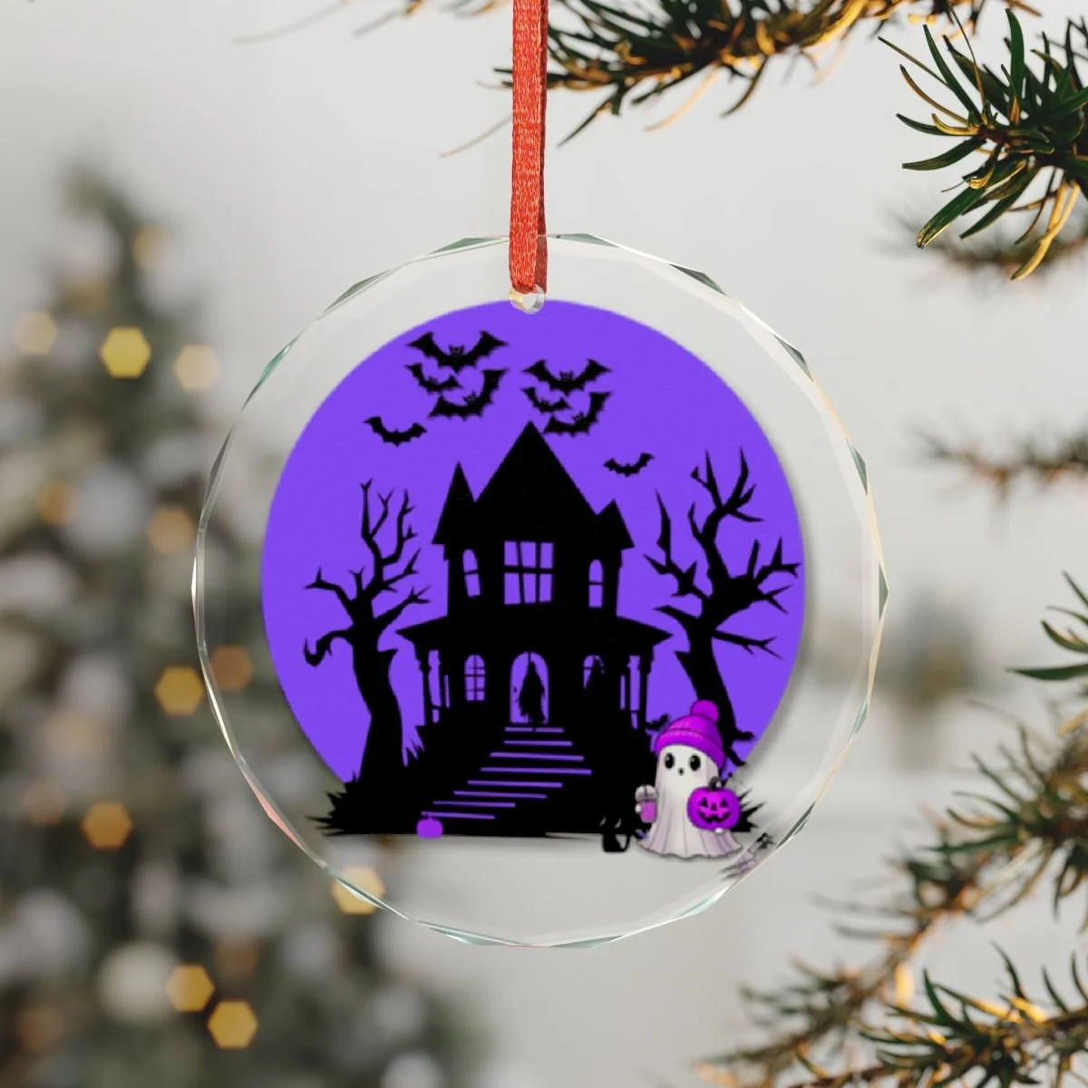 round glass ornament with beveled edges. in the middle is a purple background. in the purple is a black haunted house with black trees, black bats flying and a ghost trick or treater deciding if they want to go to the house for candy