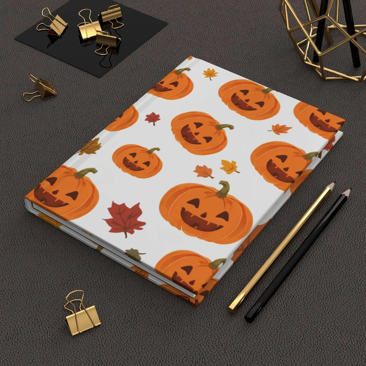 hard cover journal in white with orange smiling jack o lanterns and burgandy and orange leave randomly all over the front and back of hardcover
