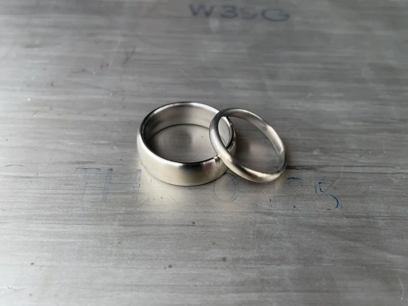 Two metal rings, one larger and one smaller, resting on a metallic surface.