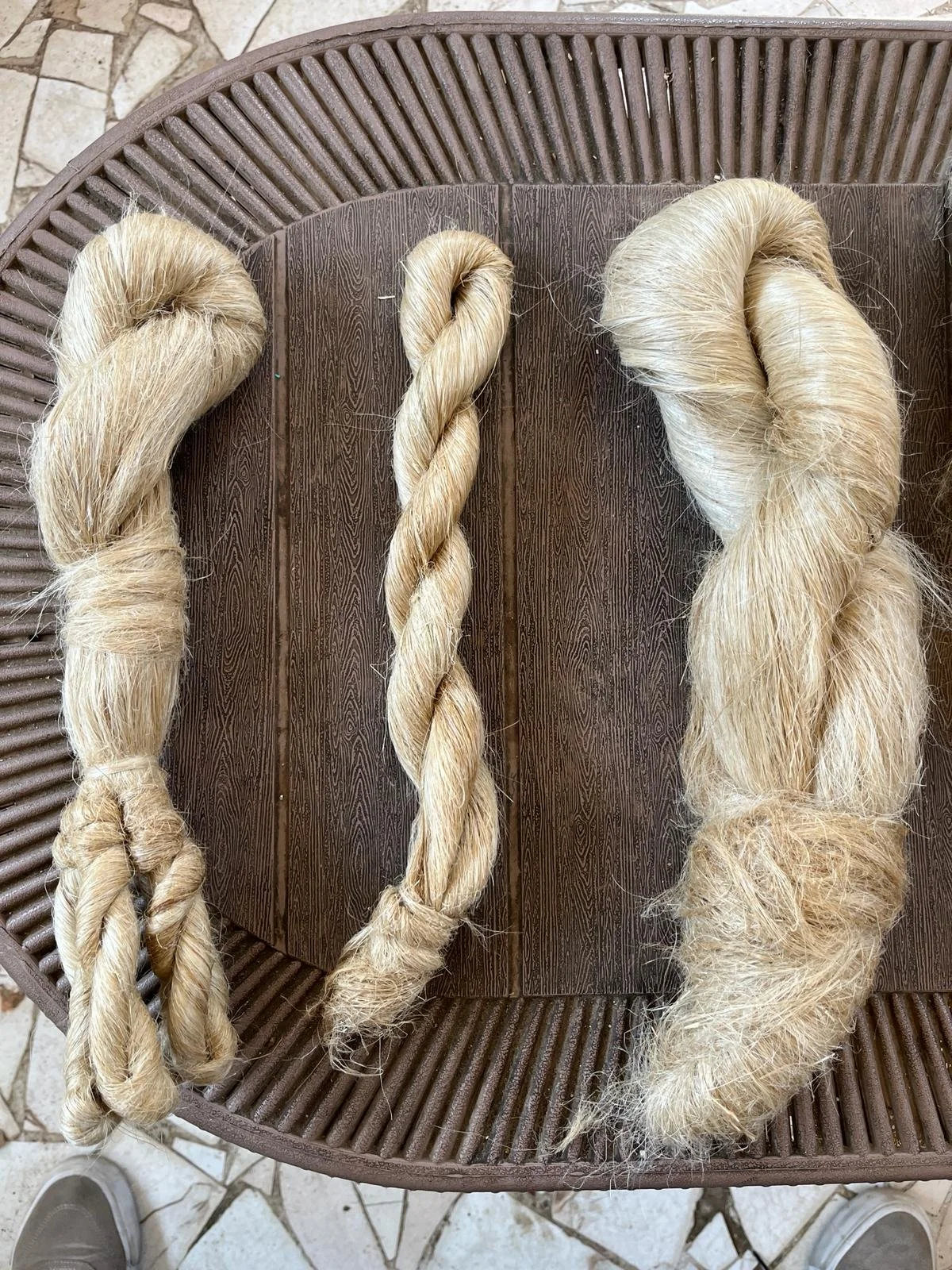 Three blonde hair extensions in different styles on a brown surface.