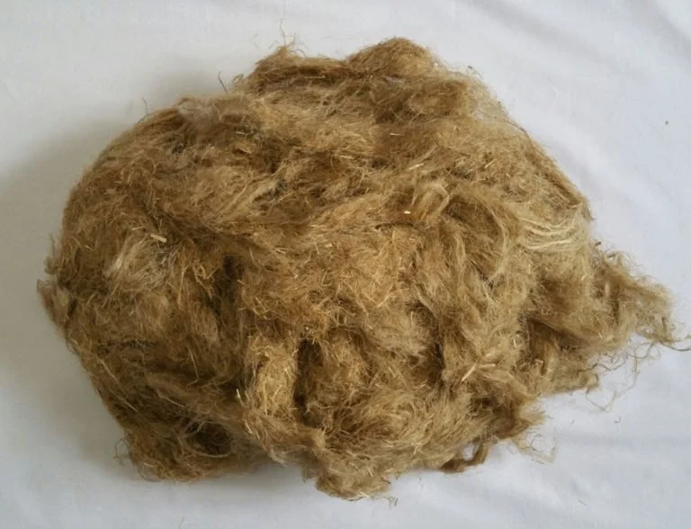 A close-up of a clump of golden-brown cat fur on a white surface.