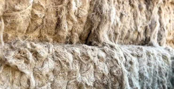 Close-up of beige, fibrous insulation material, showing its rough texture and tangled fibers.