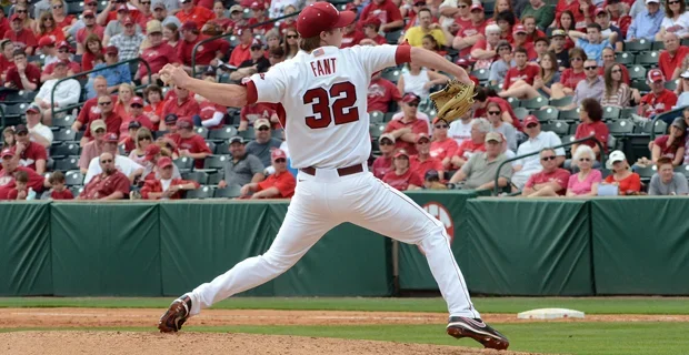 Baseball player in white and red uniform with number 32 on the back, mid-pitch on a baseball field, with a crowd of spectators in the stands.