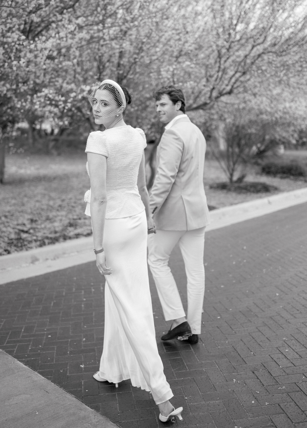 Laurie’s customers, Mariana and Carmen holding hands on a green lawn on their wedding day.