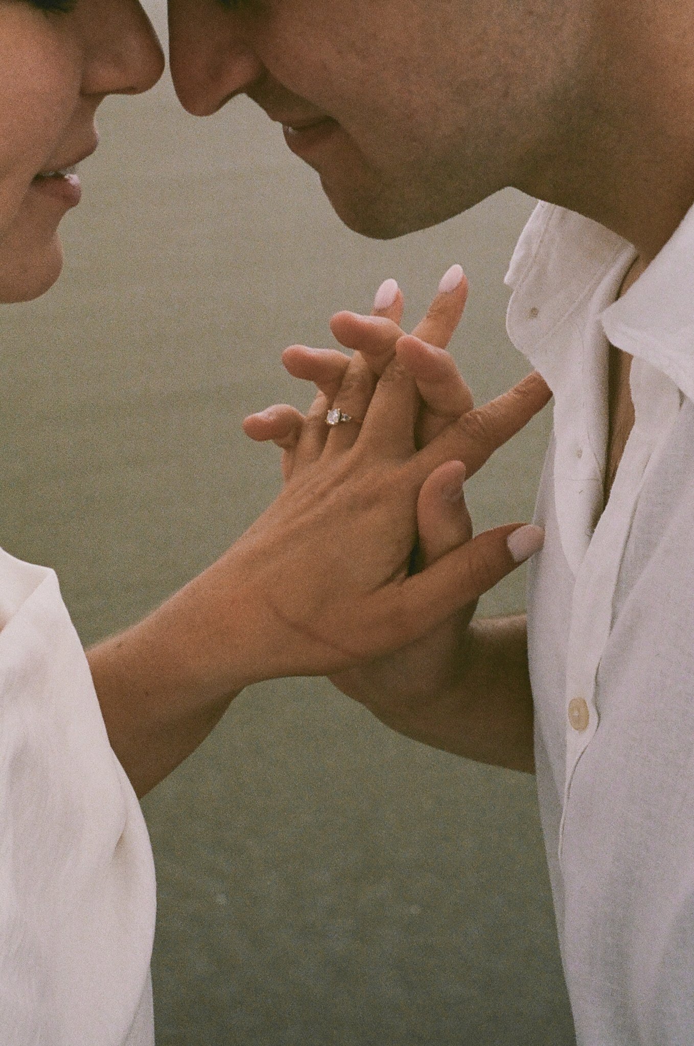 Close-up of a couple touching foreheads with hands intertwined, showing a wedding ring