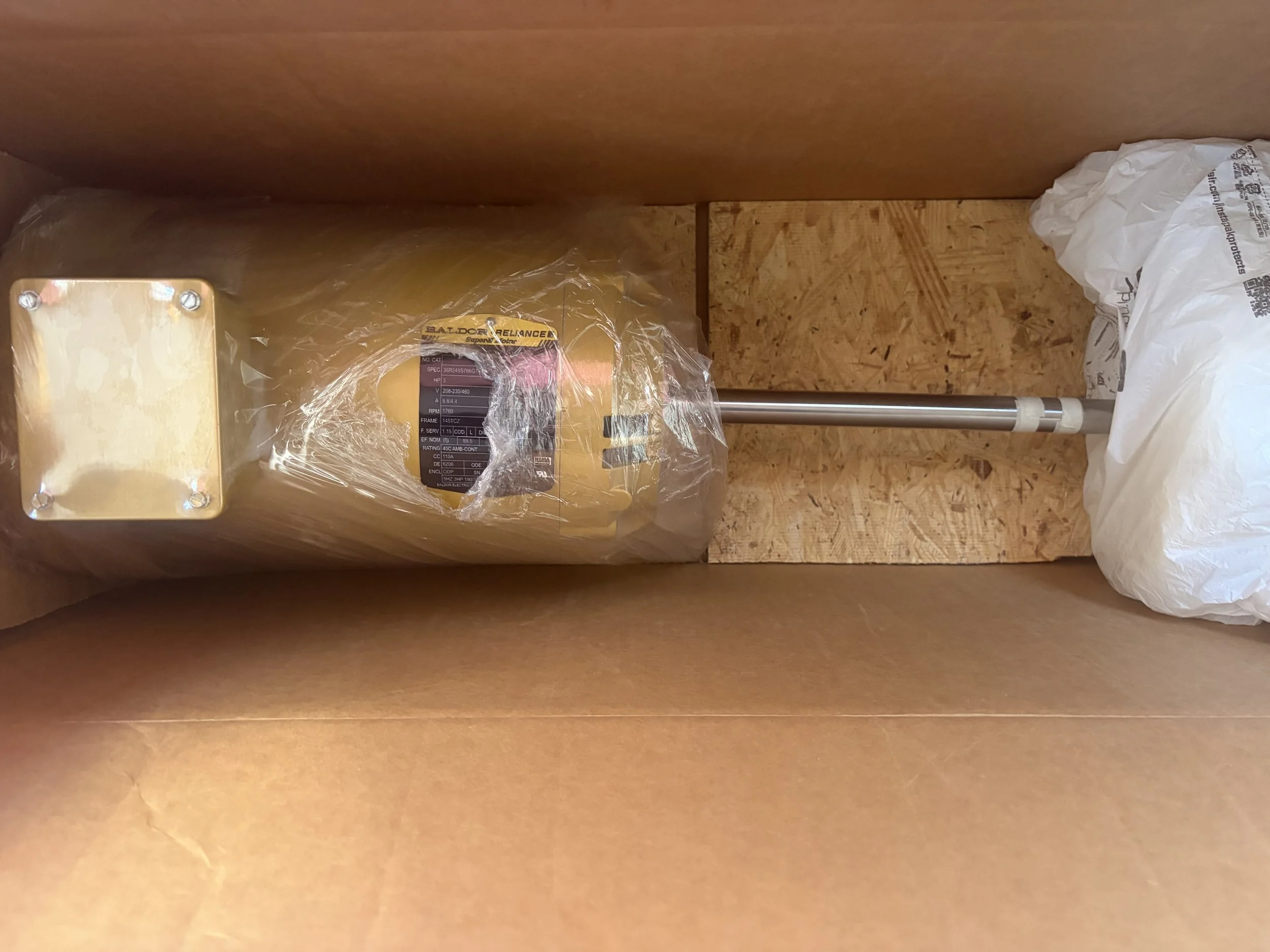 Caja de madera con un robot eléctrico dentro, envuelto en plástico, en una caja de cartón con empaques de papel en los laterales.